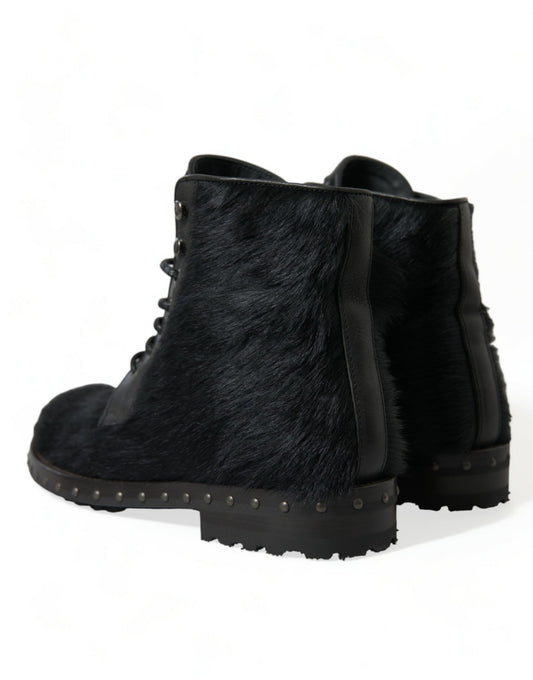 Pair of black fur lined boots with laces and metal studs on soles