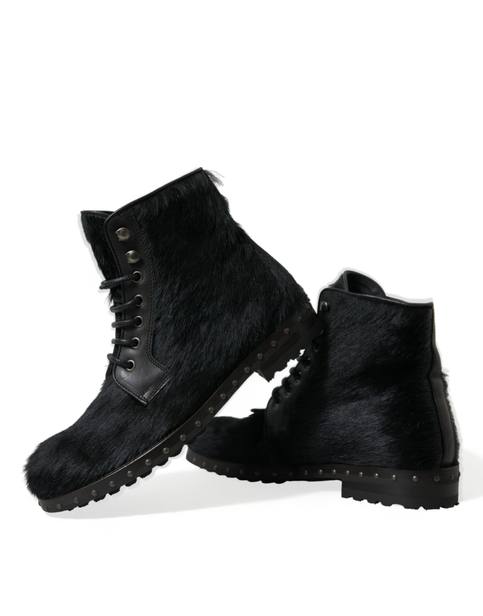 Pair of black fur boots with laces and metal studs on soles