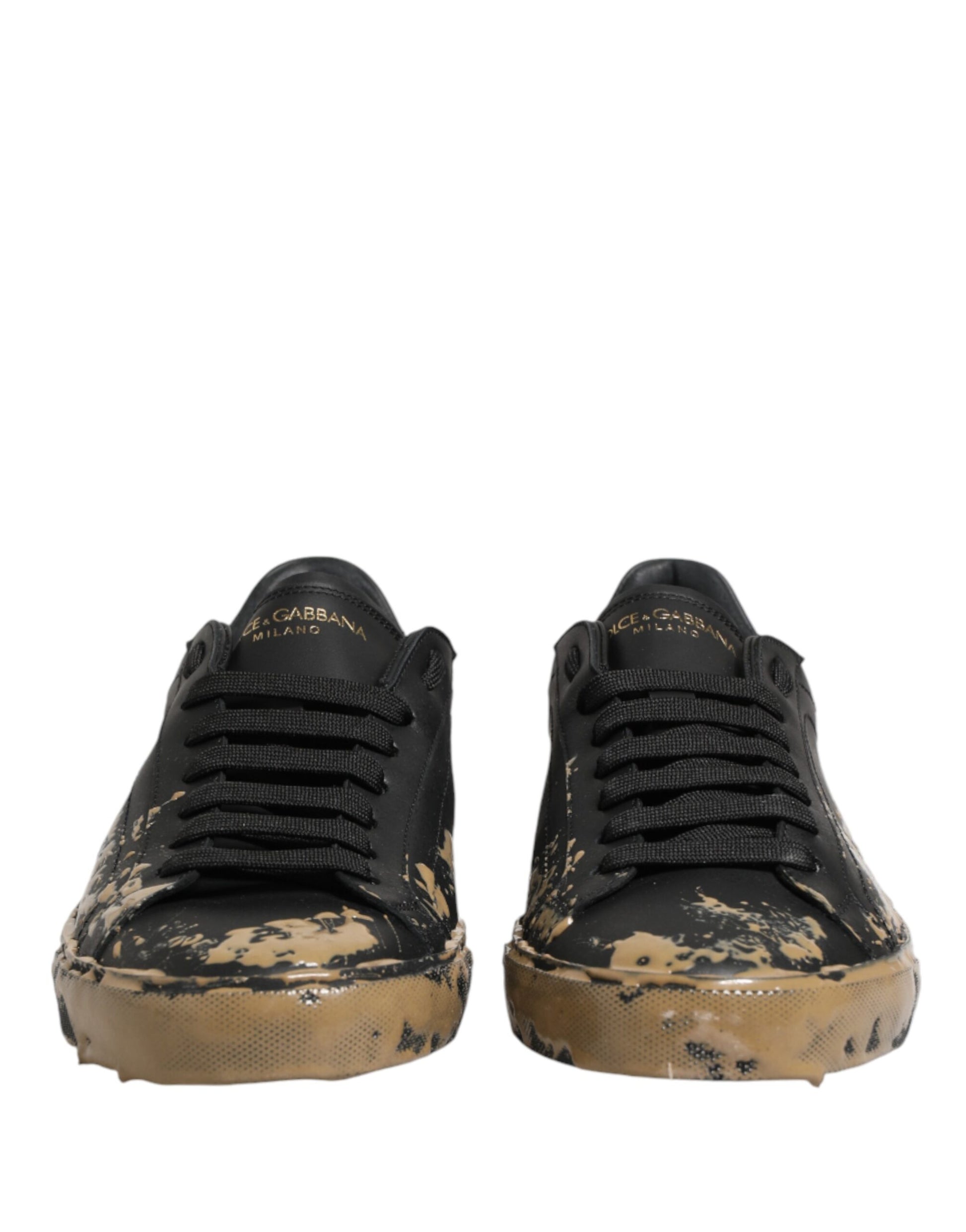 Pair of black sneakers with mud effect, featuring gold accents and a low top design