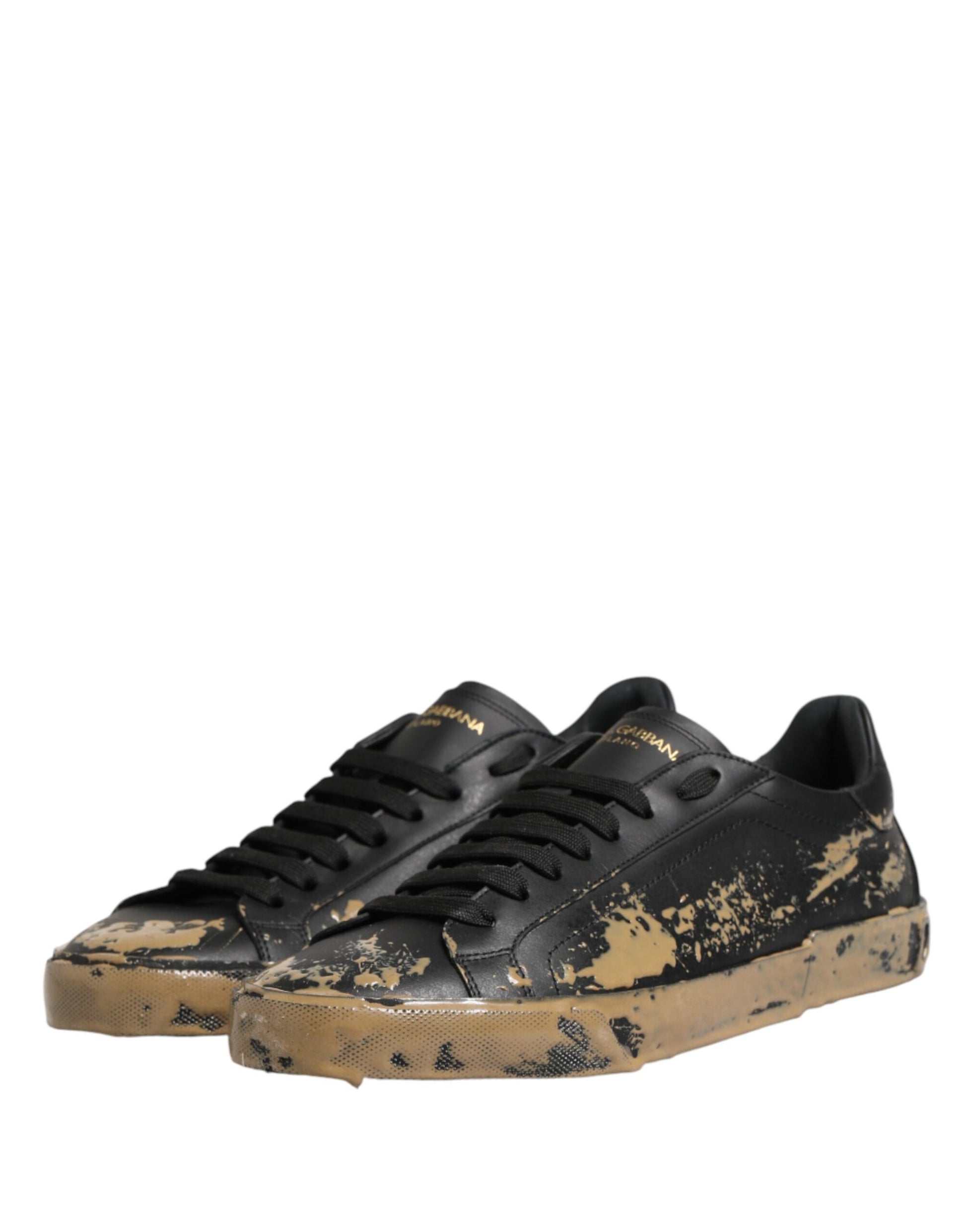 A pair of black sneakers with mud effect and gold accents, featuring a low top design