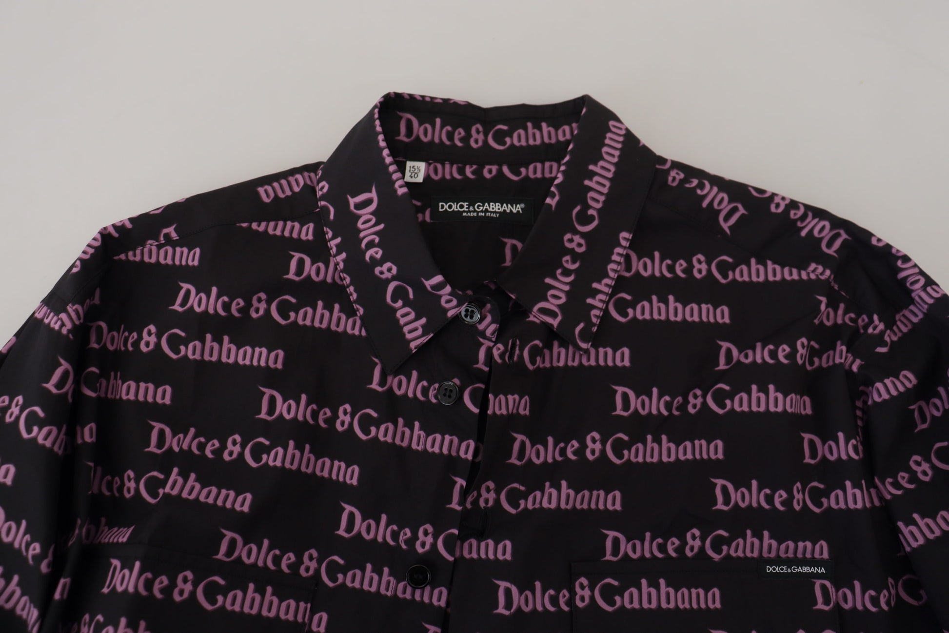 A black slim dress shirt with a purple logo pattern featuring the names "Dolce & Gabbana" repeated across it
