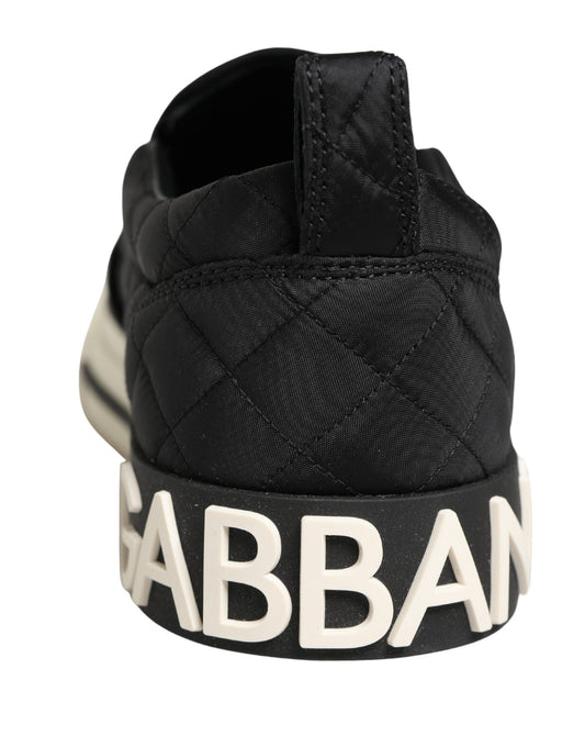 A pair of black quilted slip-on shoes with the word "GABBANA" in white letters
