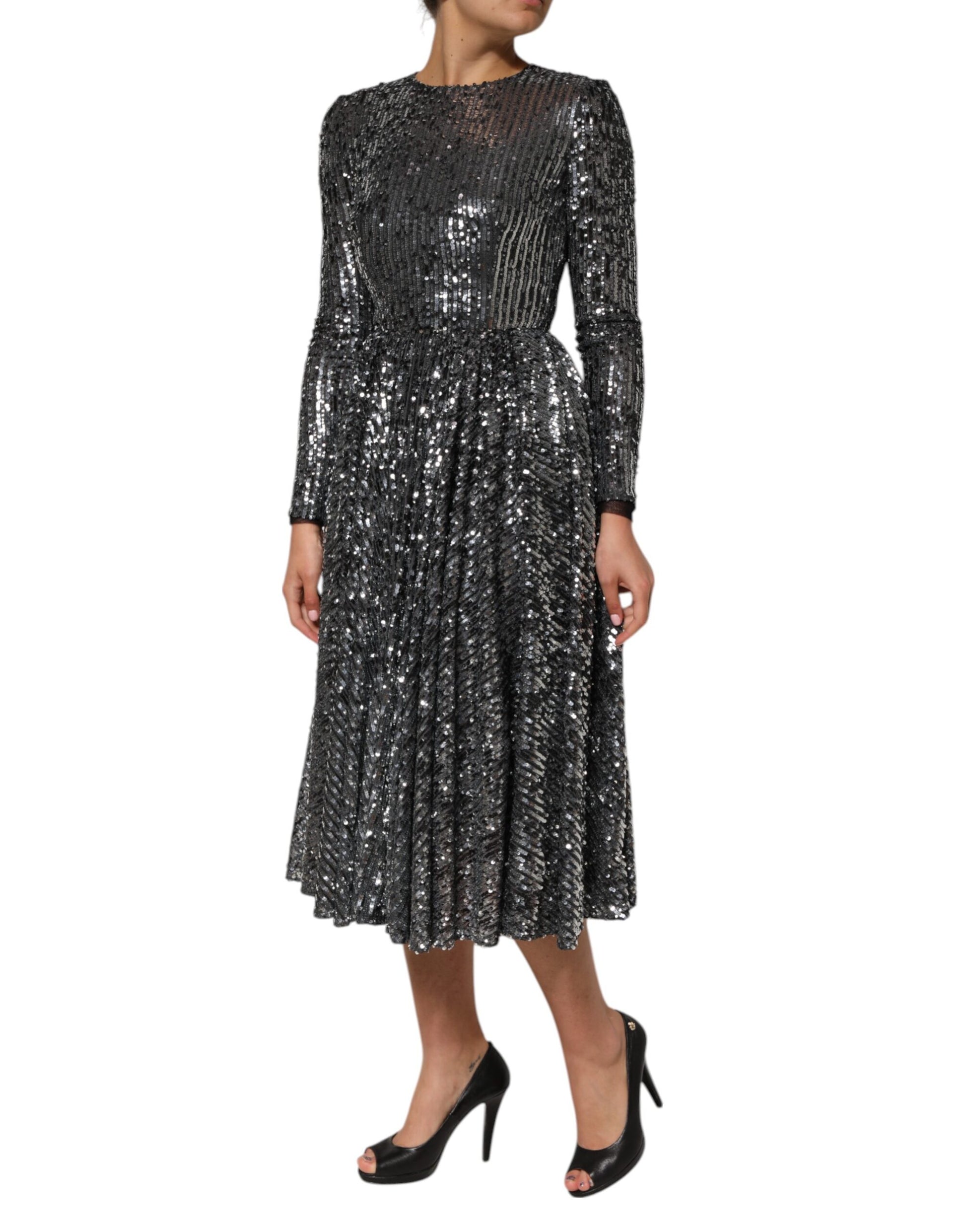 A black sequined midi dress with long sleeves and an A-line skirt. It features a glittery texture throughout