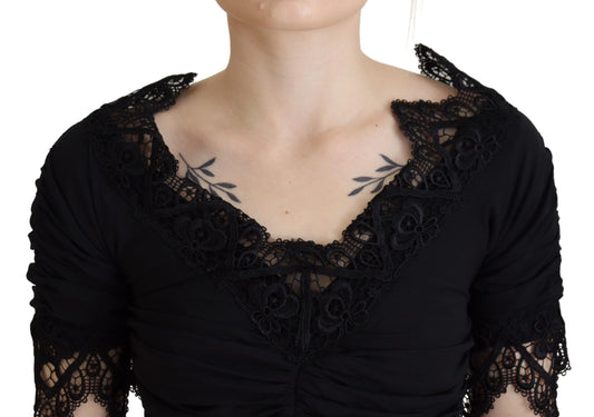 A black lace midi dress with sheer sleeves and a body-skimming silhouette