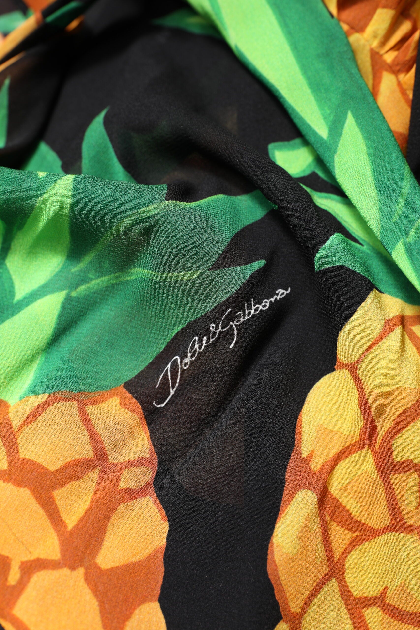 A black silk wrap dress with a pineapple print and draped design