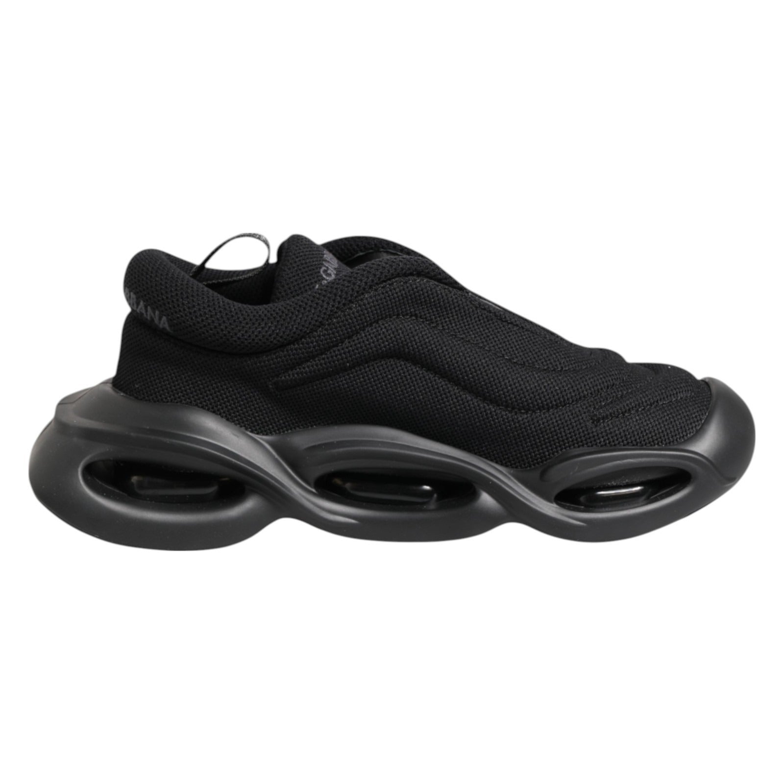 A pair of black slip-on shoes with a low top and wave design on the sole