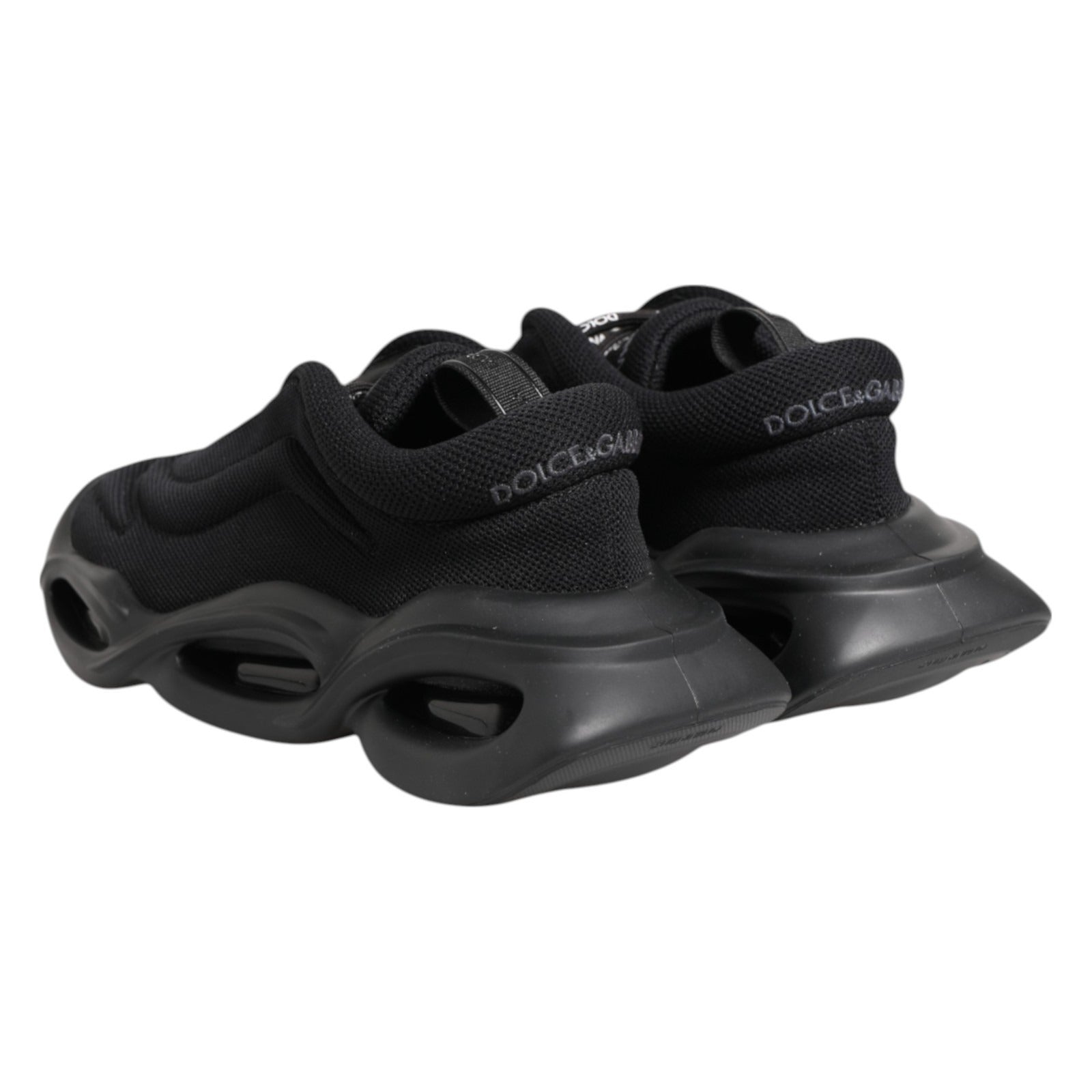 Pair of black slip-on shoes with white soles and laces, featuring the Dolce & Gabbana logo