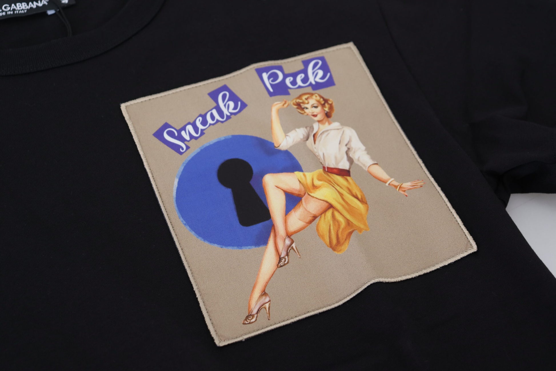 Black t-shirt with embroidered design featuring a woman in a skirt dancing with a key