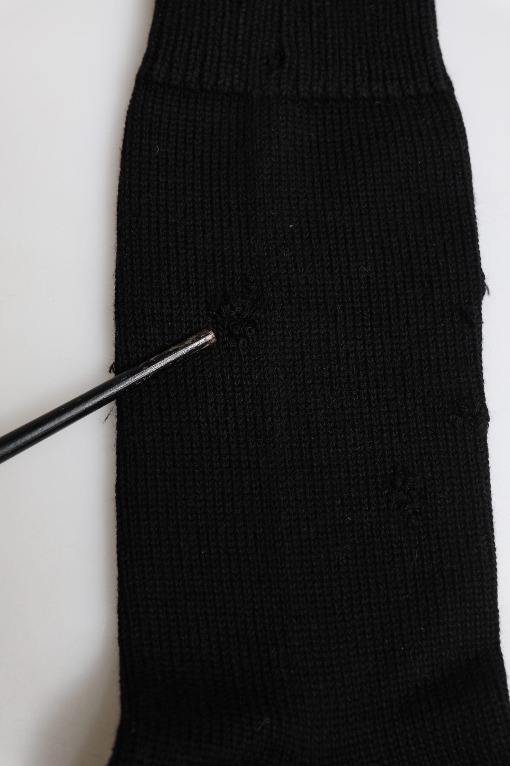 Black knitted sock on white surface