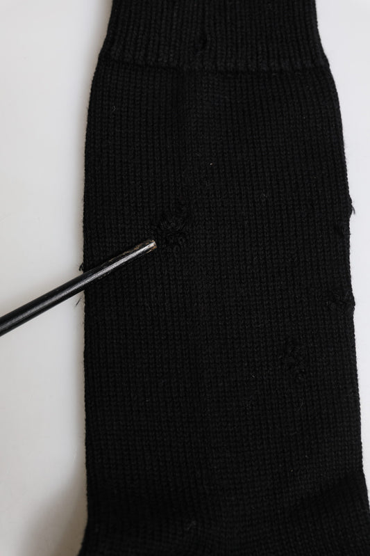 Black knitted sock on white surface