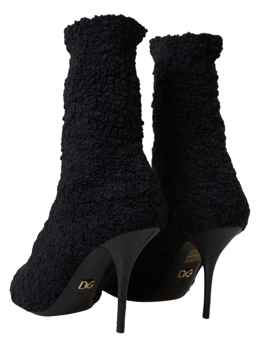 Pair of black high heel boots with fur trim and a gold logo on the side