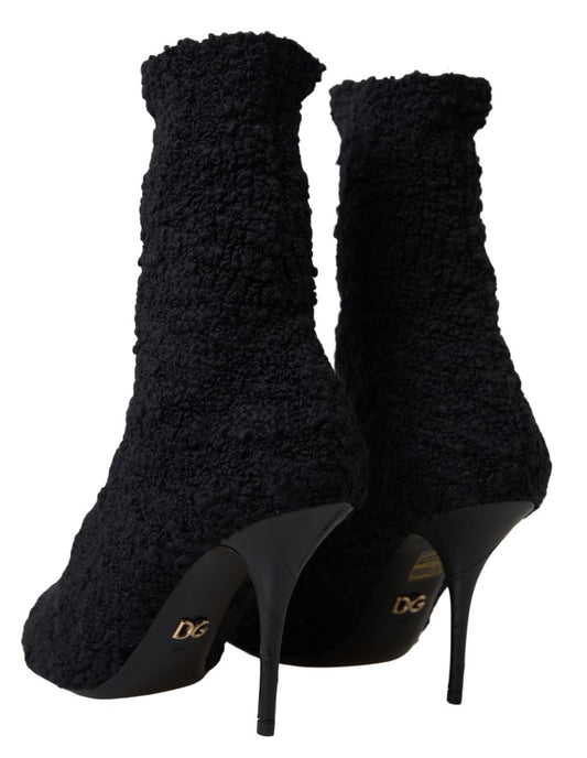 Pair of black high heel boots with fur trim and a gold logo on the side