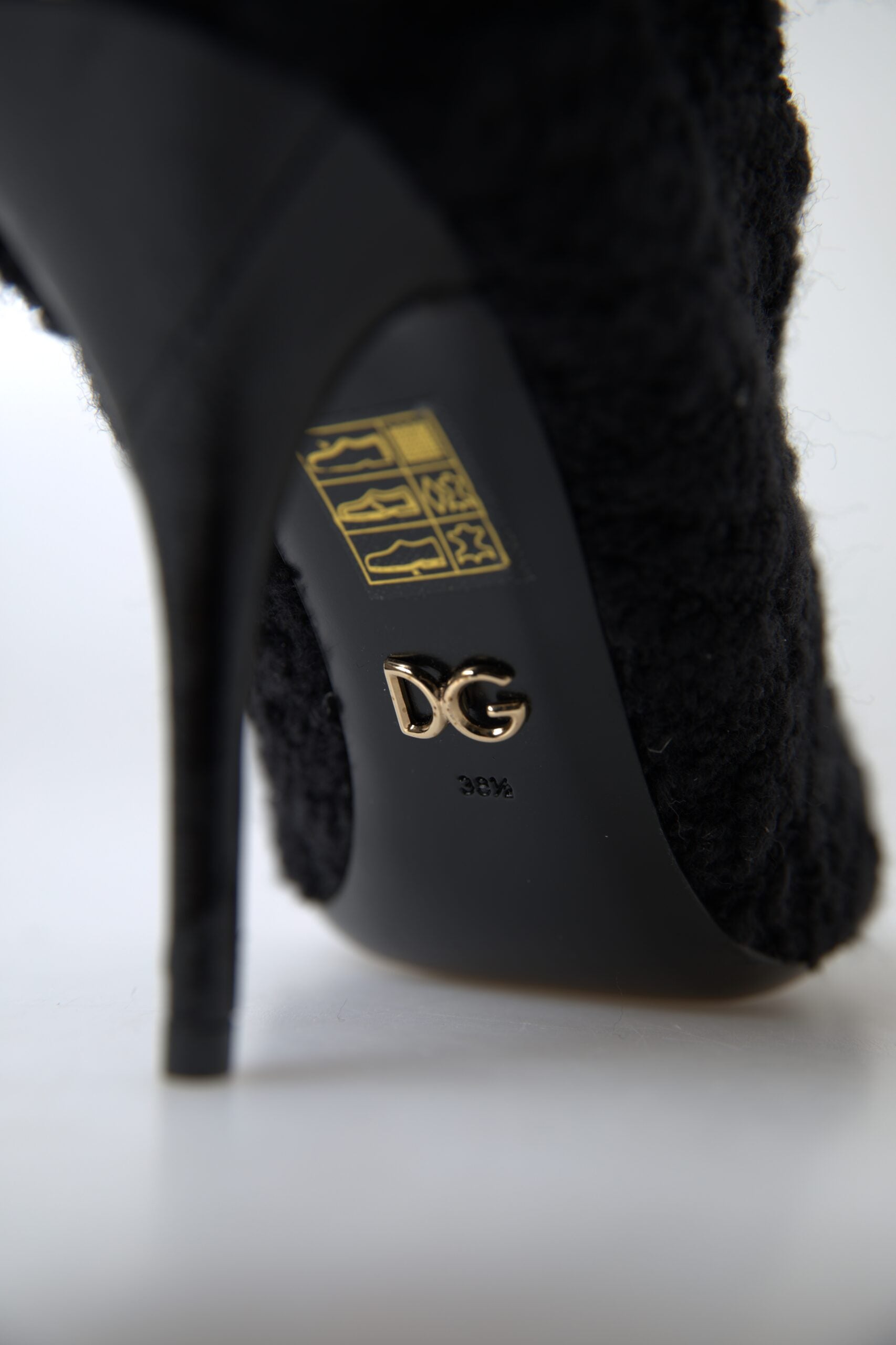 Black high heel shoe with a gold logo on the insole