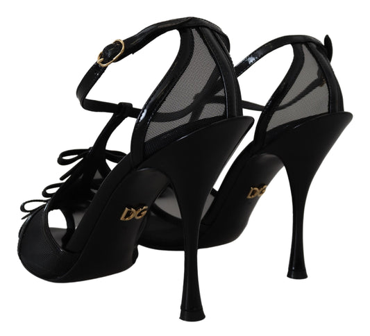 Pair of black high heel shoes with gold accents and a bow on top