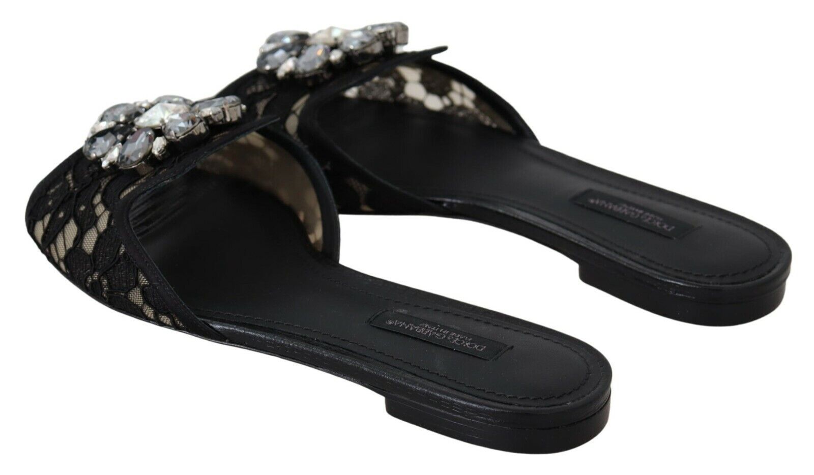 Pair of black sandals with embellishments and a bow on top