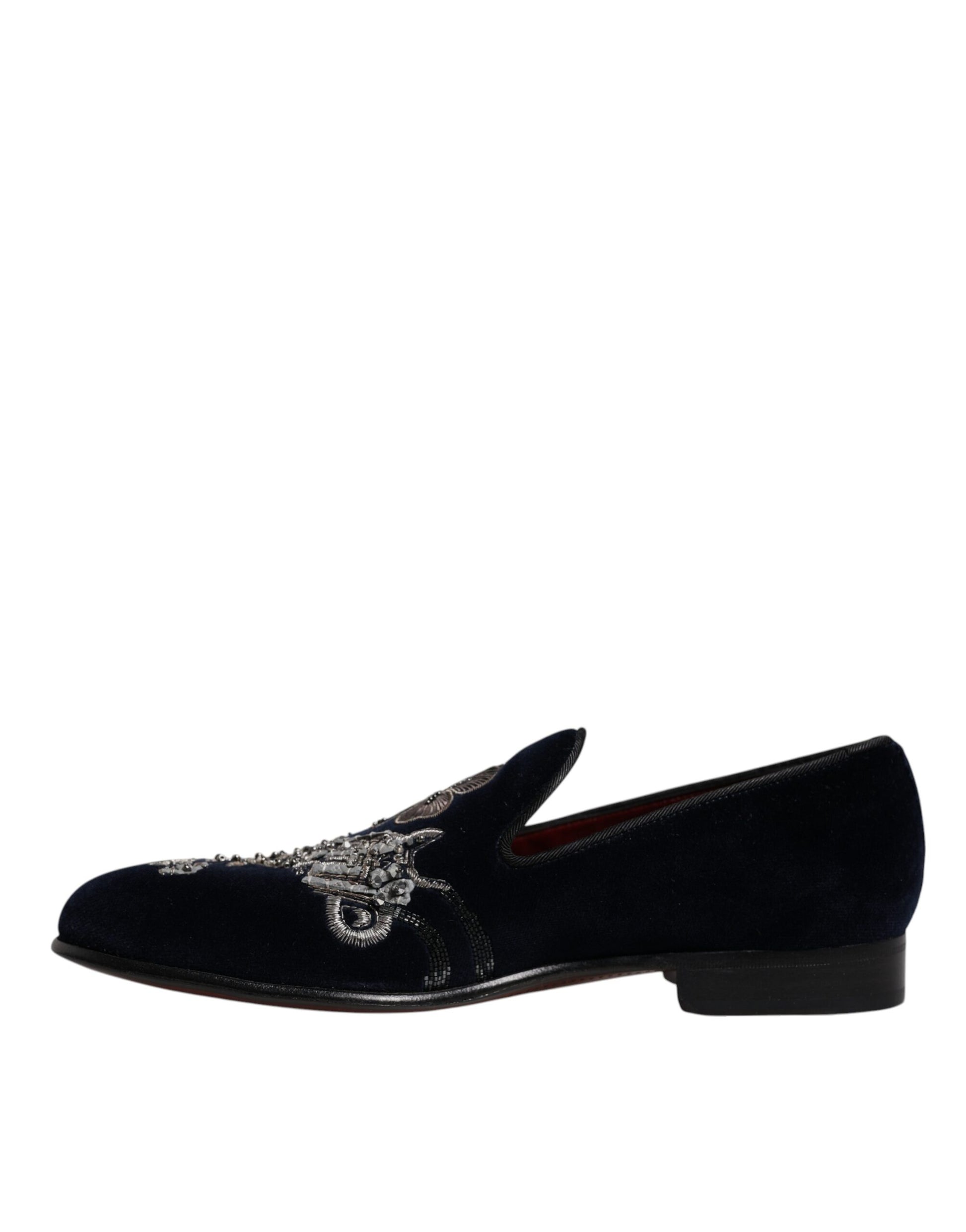 A pair of black velvet loafers with floral embroidery and a gun design on the toe