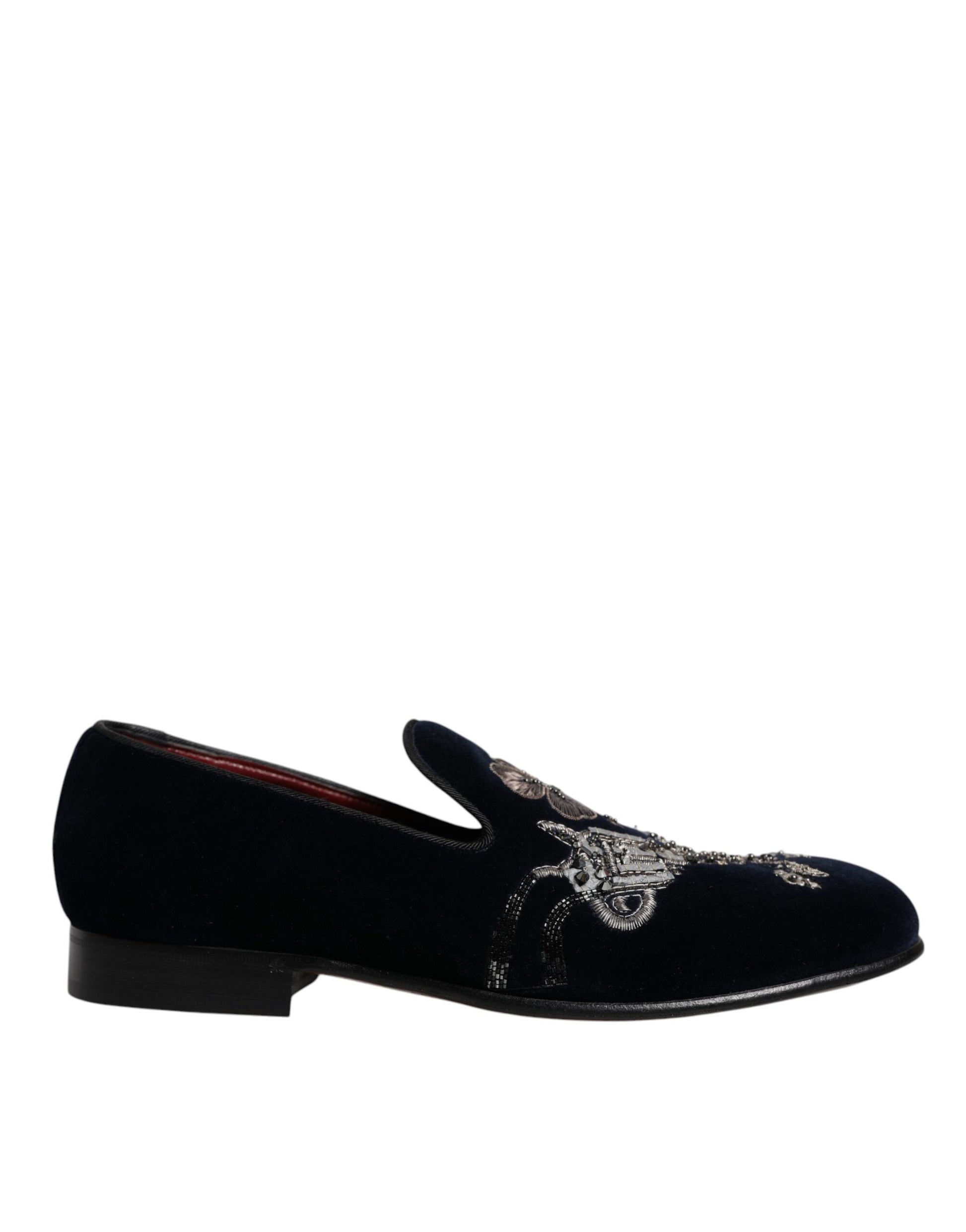 A pair of black velvet loafers with floral embroidery and a gun design on the toe