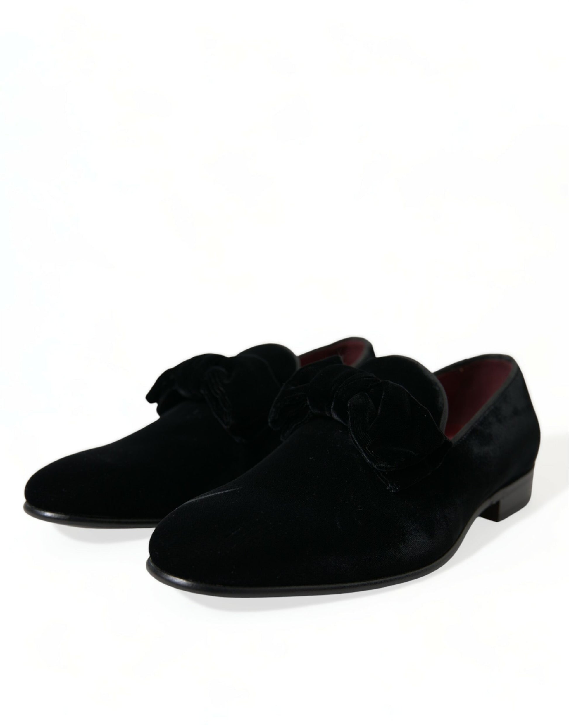 Pair of black velvet loafers with red accents and a bow tie design on top