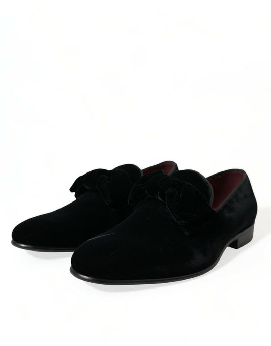Pair of black velvet loafers with red accents and a bow tie design on top