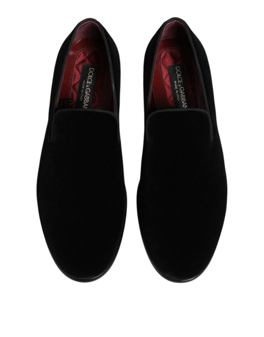 Pair of black velvet loafers with red accents, featuring a gold buckle and logo