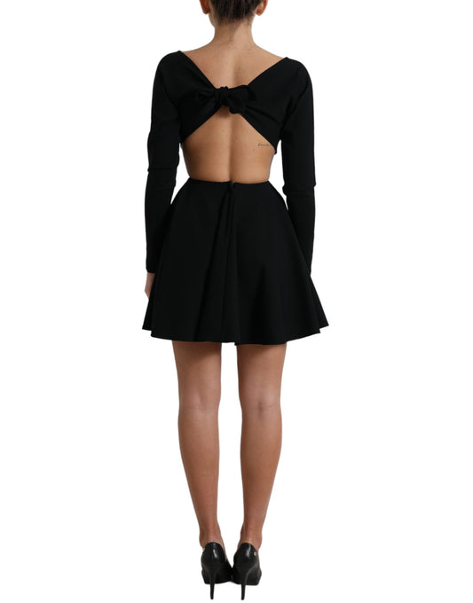 A black dress with cutouts on the back and sides. It features long sleeves and is made of viscose material