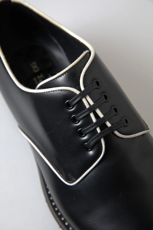 A pair of black leather dress shoes with white laces and a bow tie design on the vamp