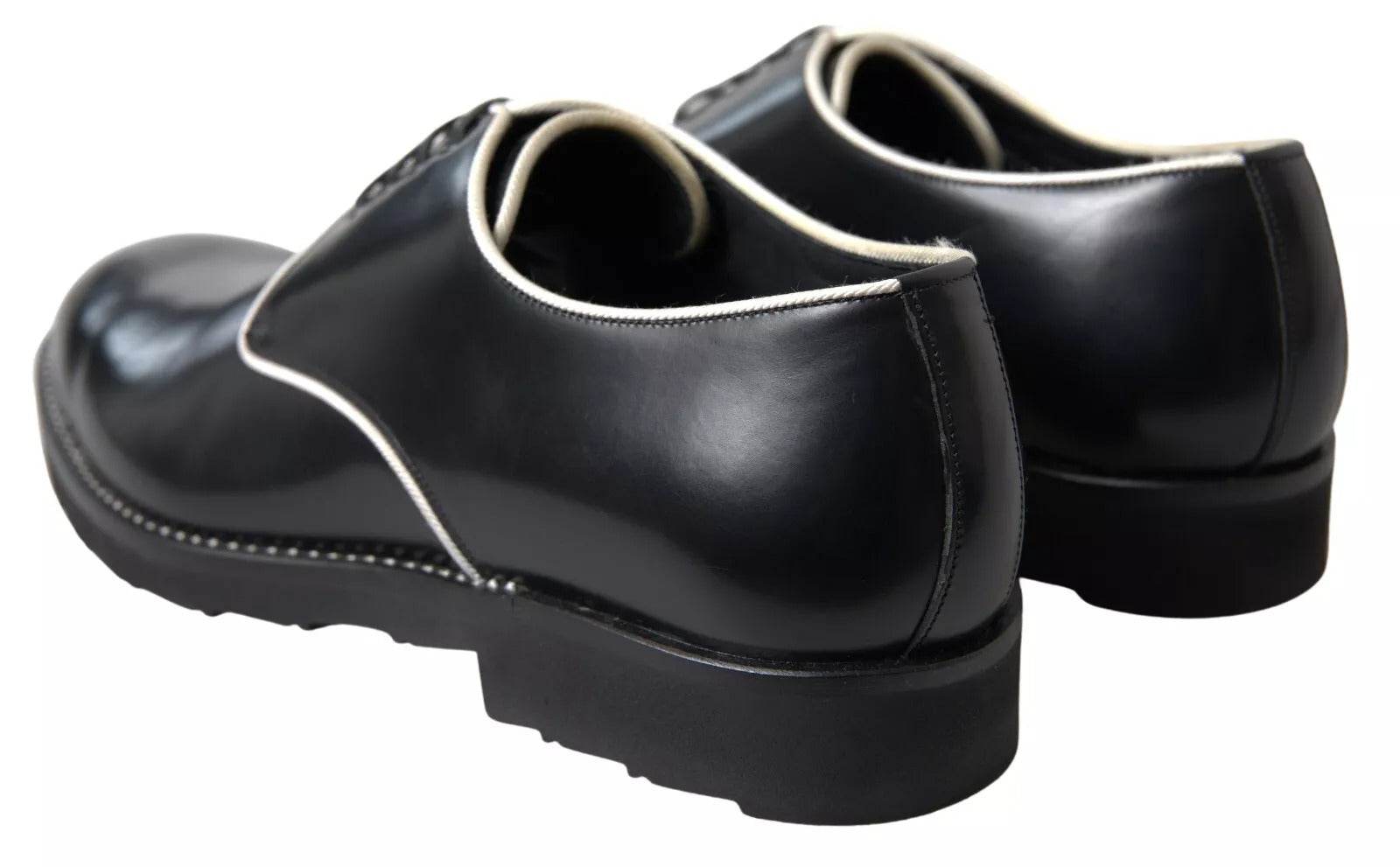Pair of black leather formal dress shoes with white laces and soles, featuring a stylized design