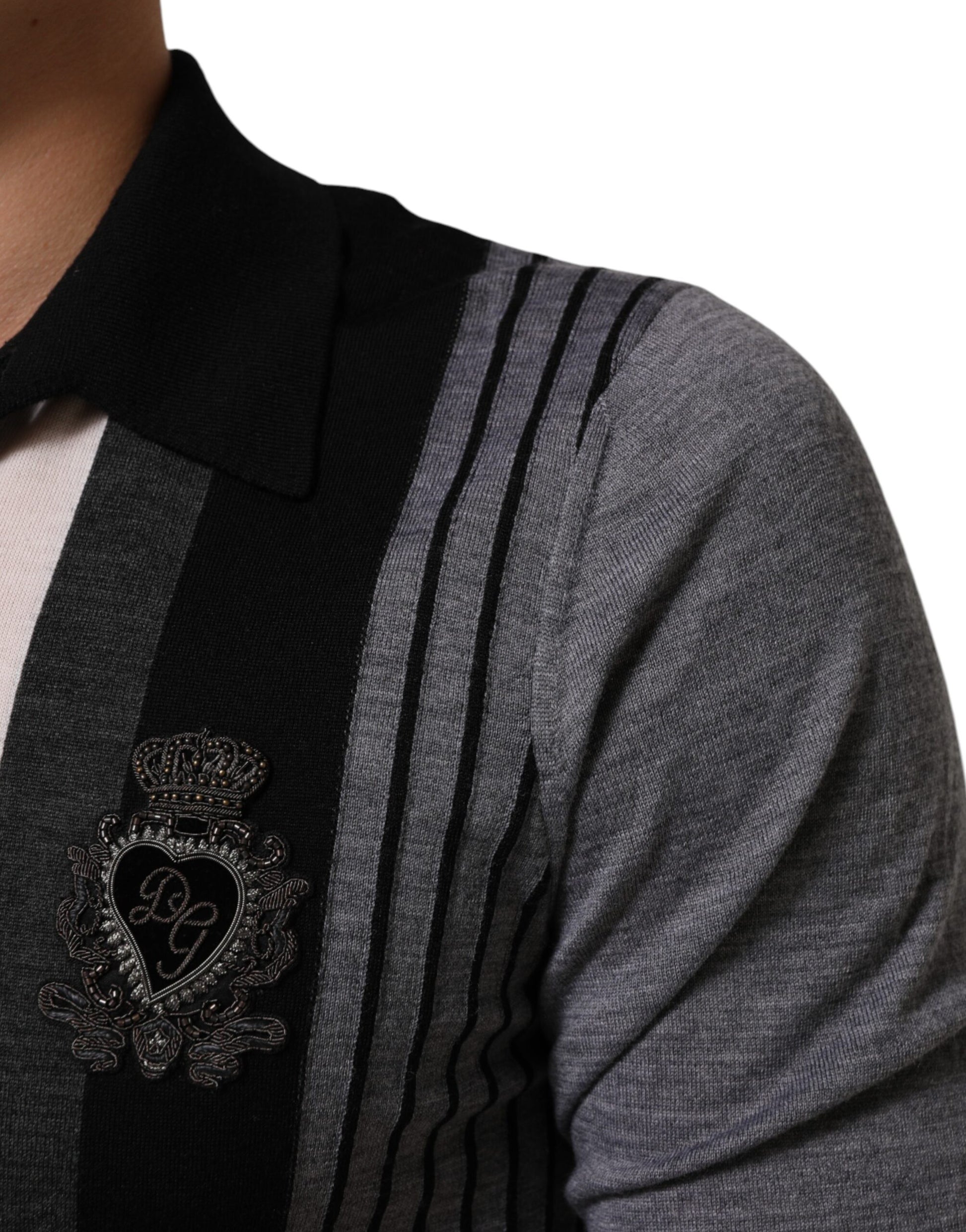A person wearing a sweater vest with a heart embroidery on the left side of the chest area