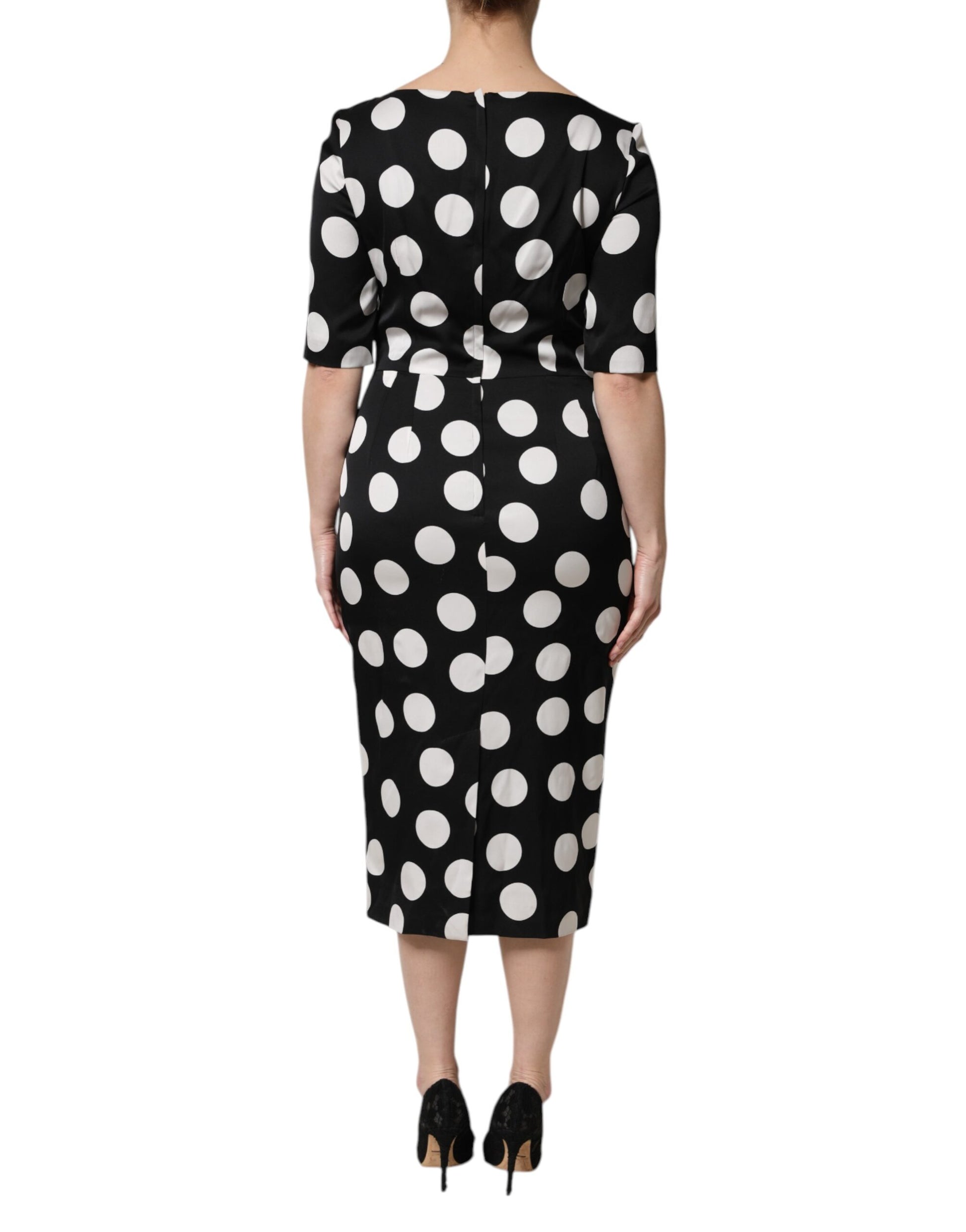 A black midi dress with white polka dots, featuring a fitted bodice and flared skirt