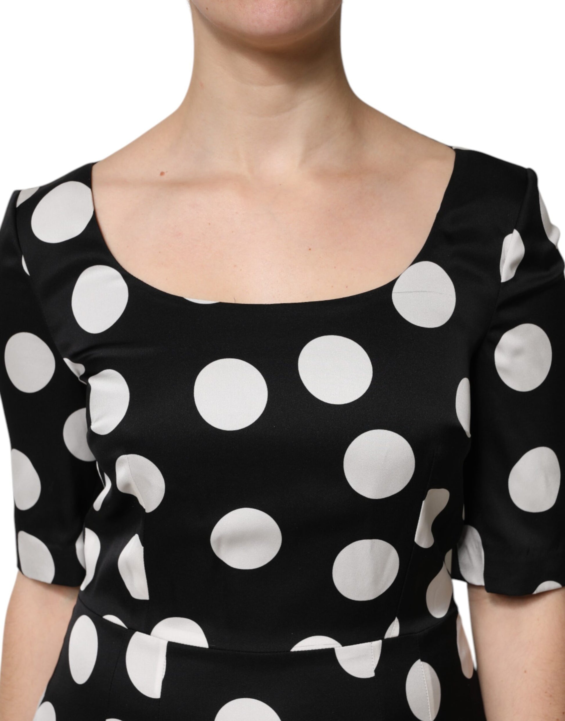A black midi dress with white polka dots, featuring a sheath silhouette