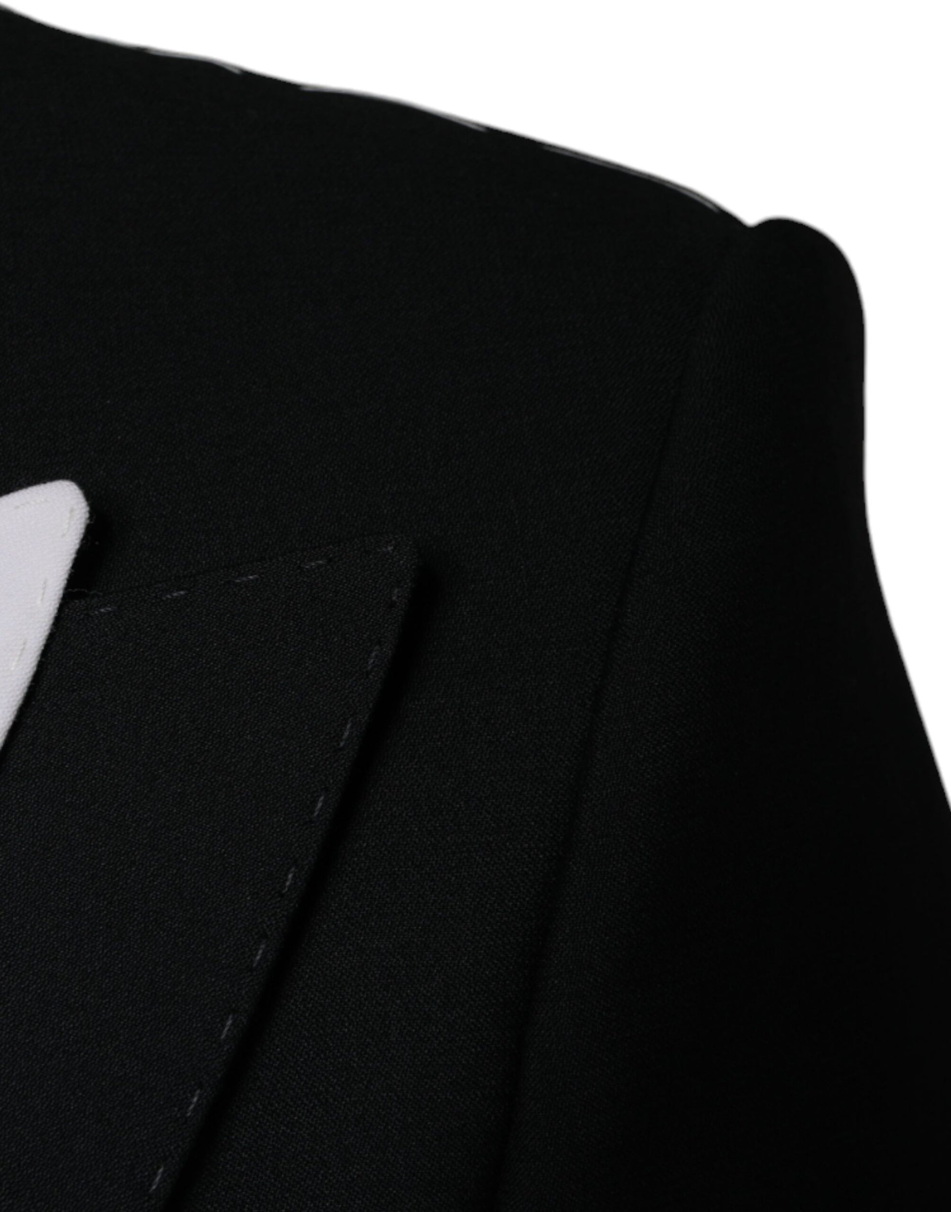 A black single-breasted blazer with white trim and a lapel pin
