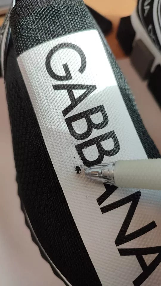 A pair of black and white slip-on shoes with the brand name "Dolce & Gabbana" visible on the side