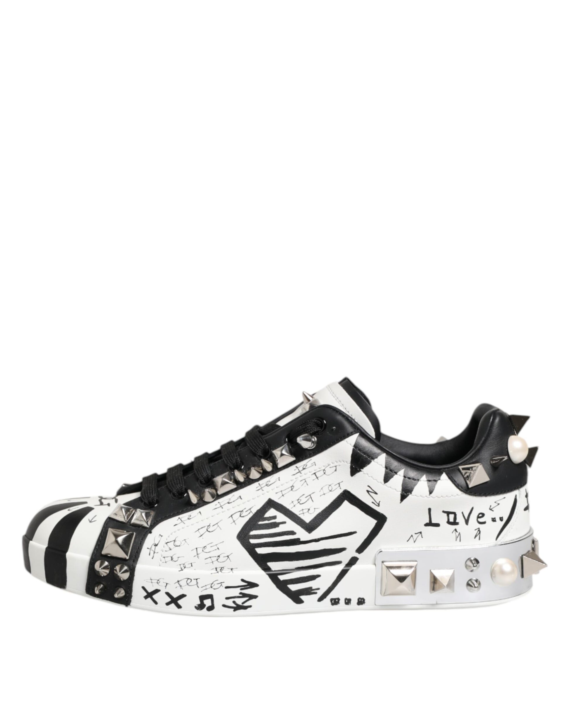 A pair of black and white studded low top sneakers with a graphic design on the side