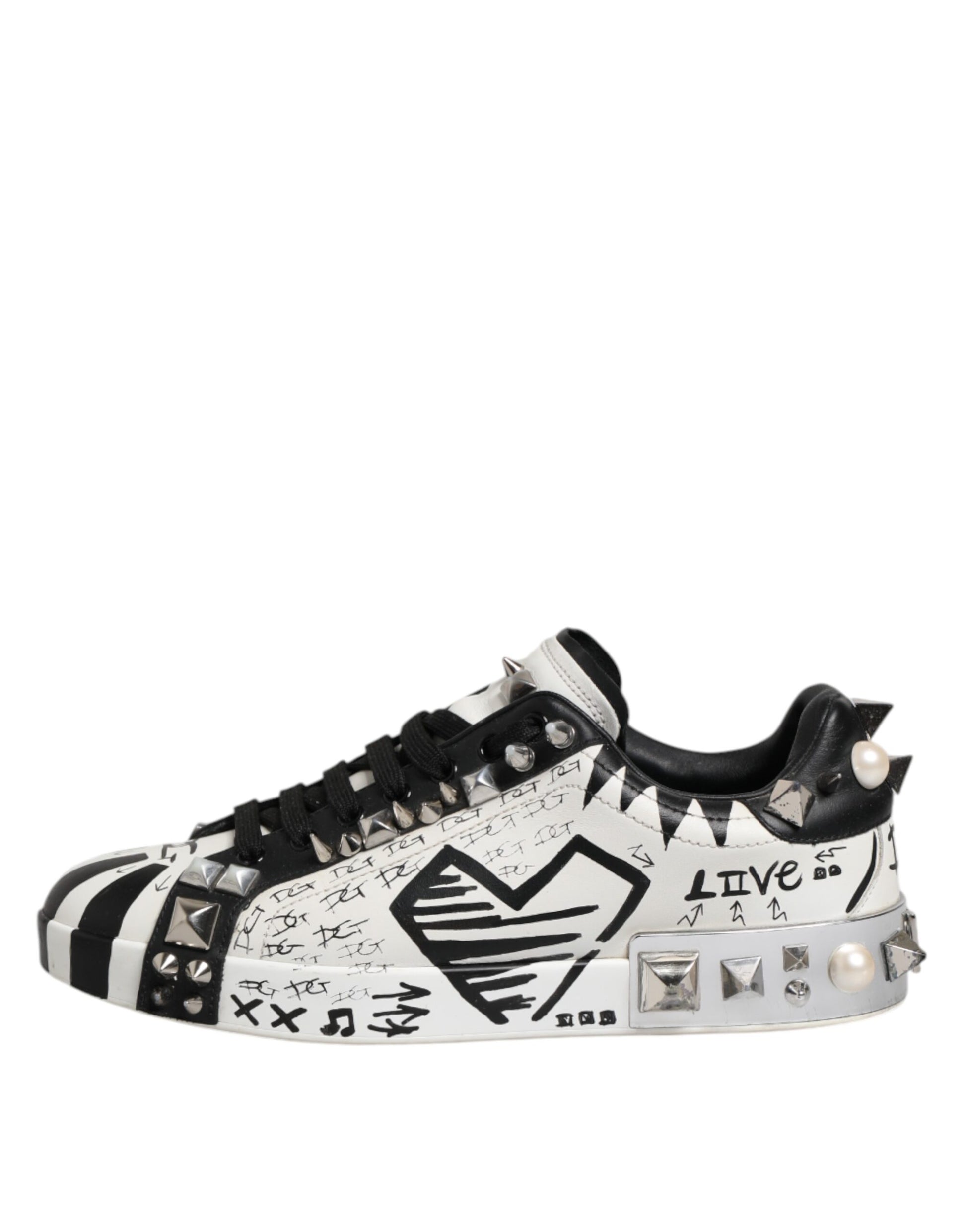 A pair of black and white studded low top sneakers with a heart design on the side