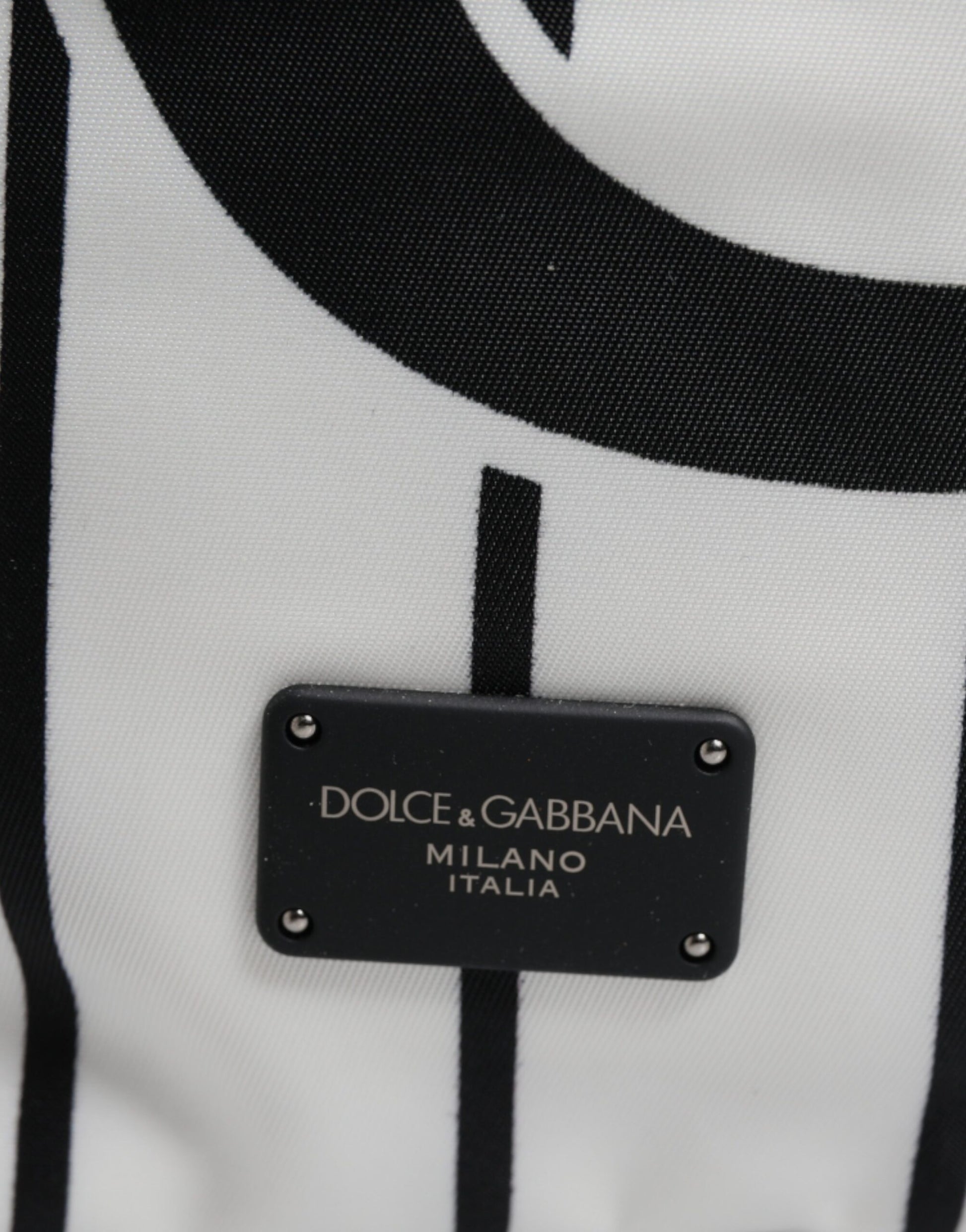 Black tag on white fabric with brand name in gold lettering