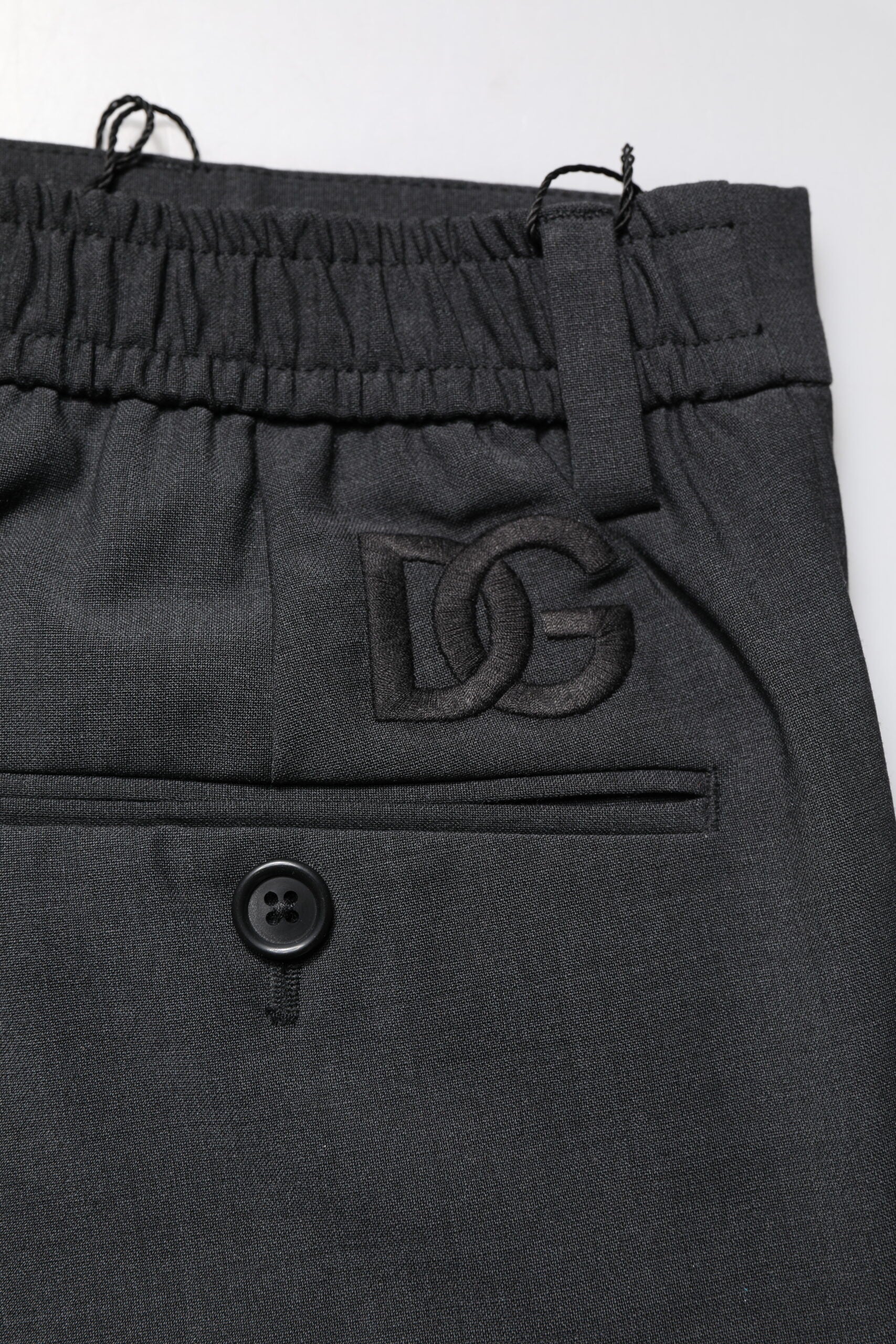 A pair of black wool dress pants with a slim fit, featuring the Dolce & Gabbana logo on the waistband