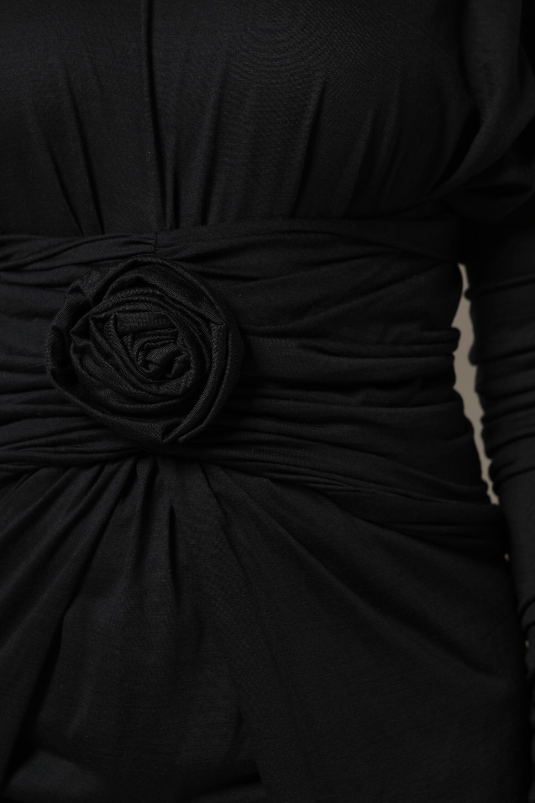 A black wool midi dress with long sleeves and a floral embellishment