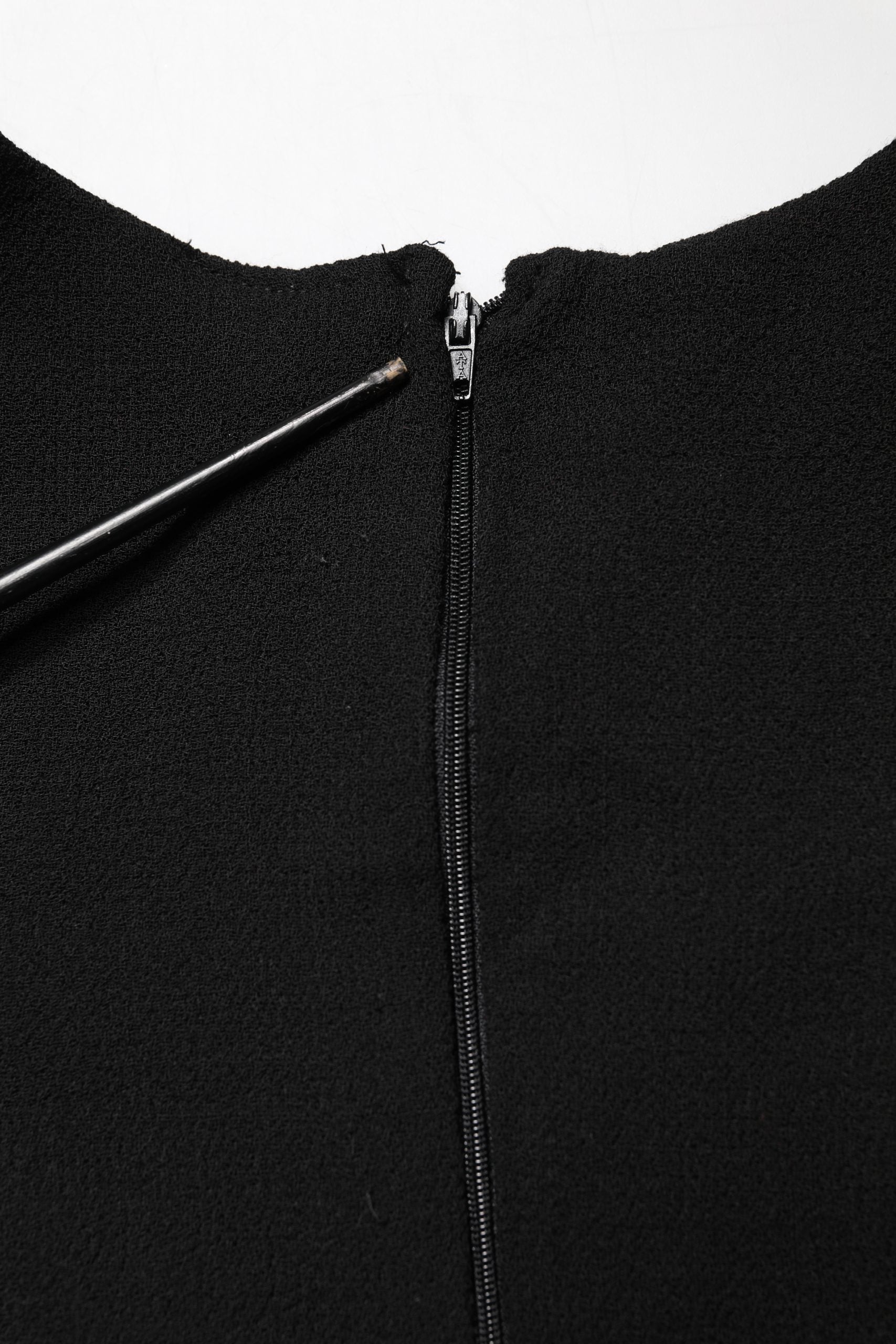 A black wool midi dress with a zipper and a sacred heart patch on the front
