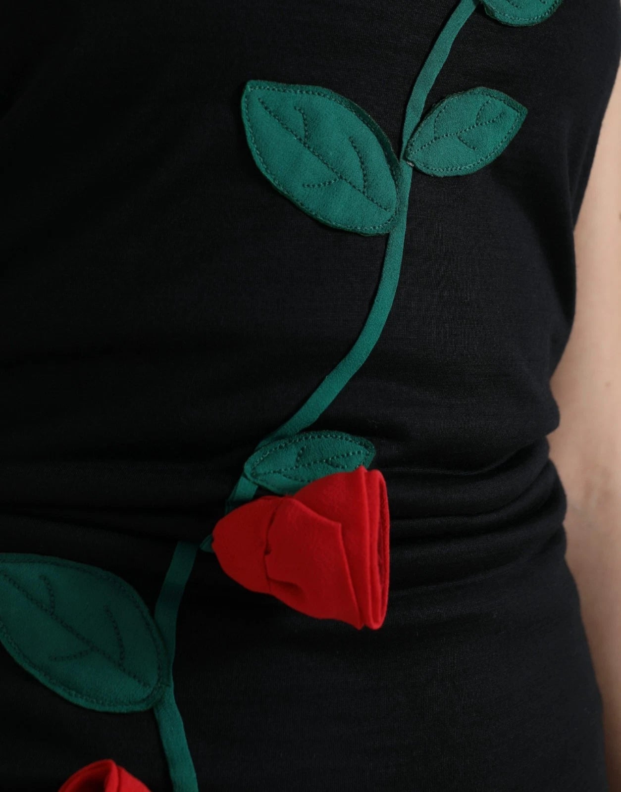 A black wool sleeveless dress with a rose applique design on the front
