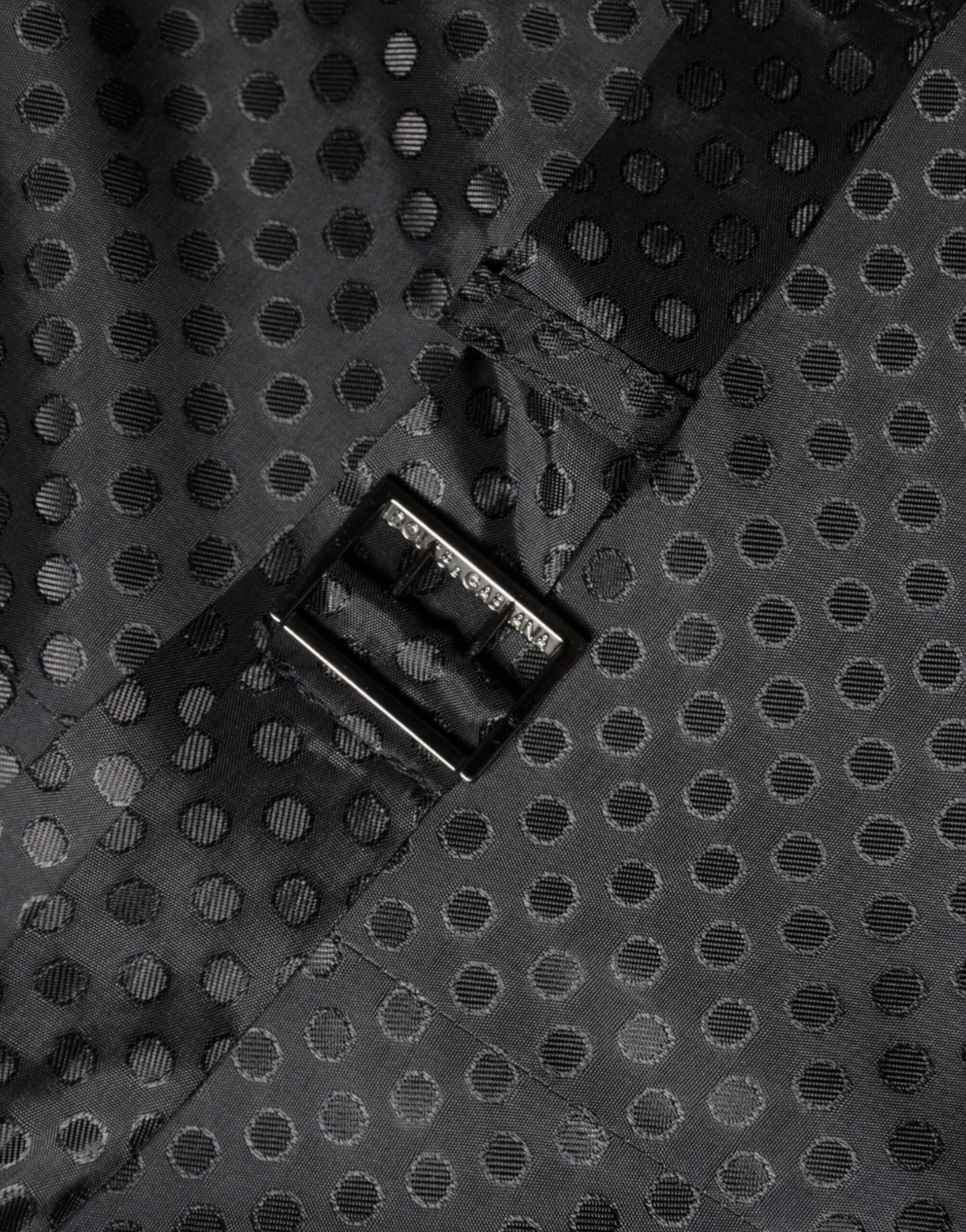 A black wool waistcoat with a textured pattern and a silver logo on the left side