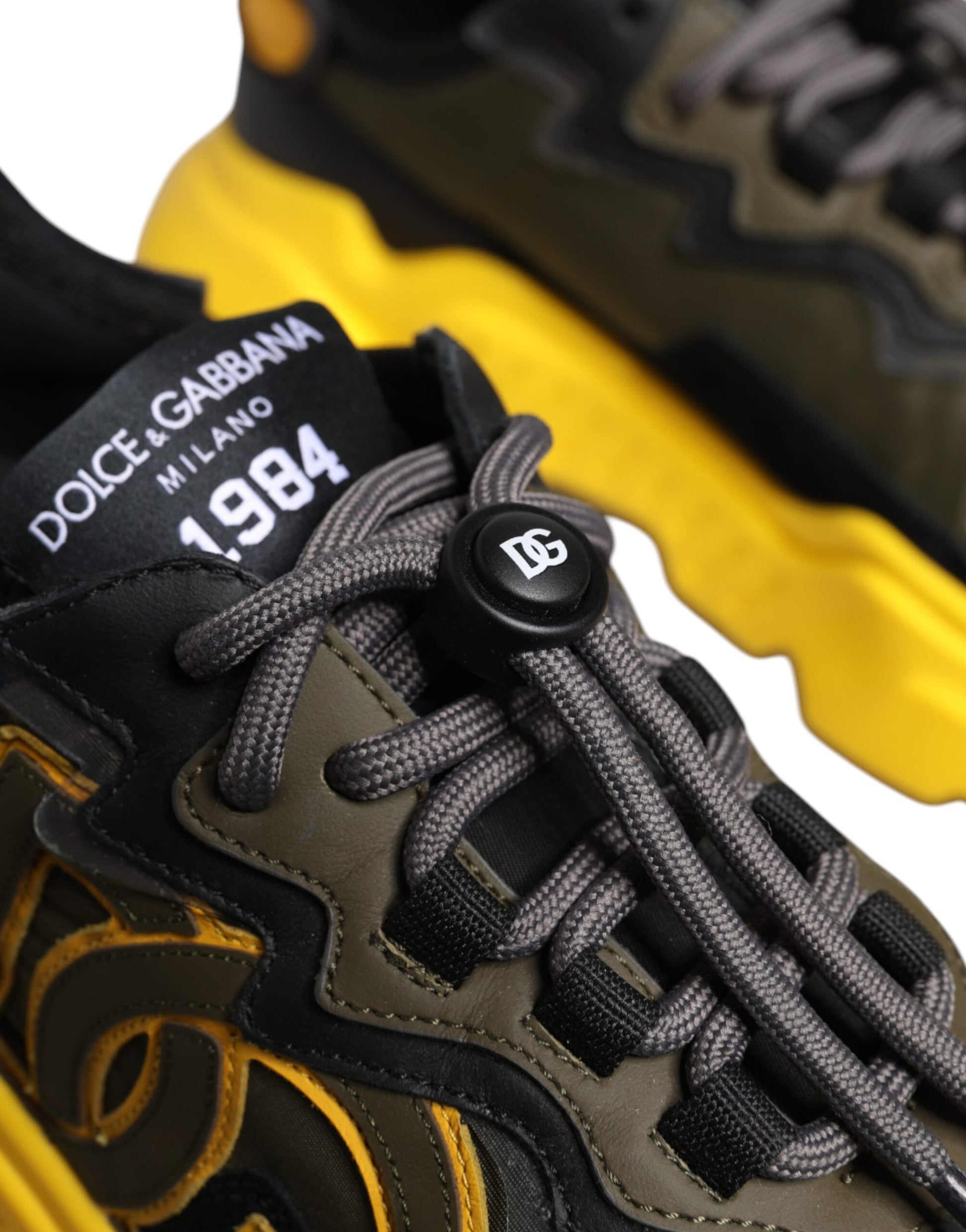 A pair of black yellow sneakers with a logo on the tongue and laces