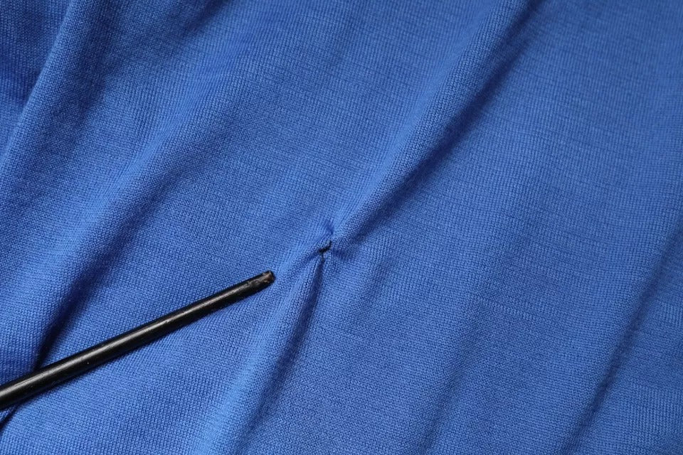 Black sewing needle on blue fabric