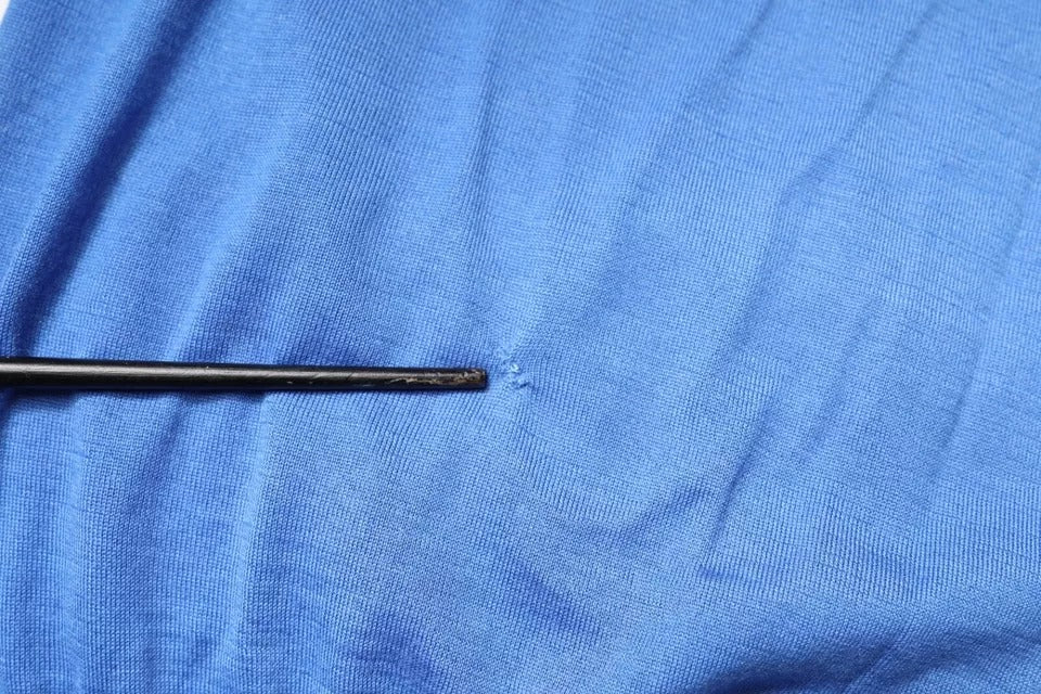 Black sewing needle on blue fabric