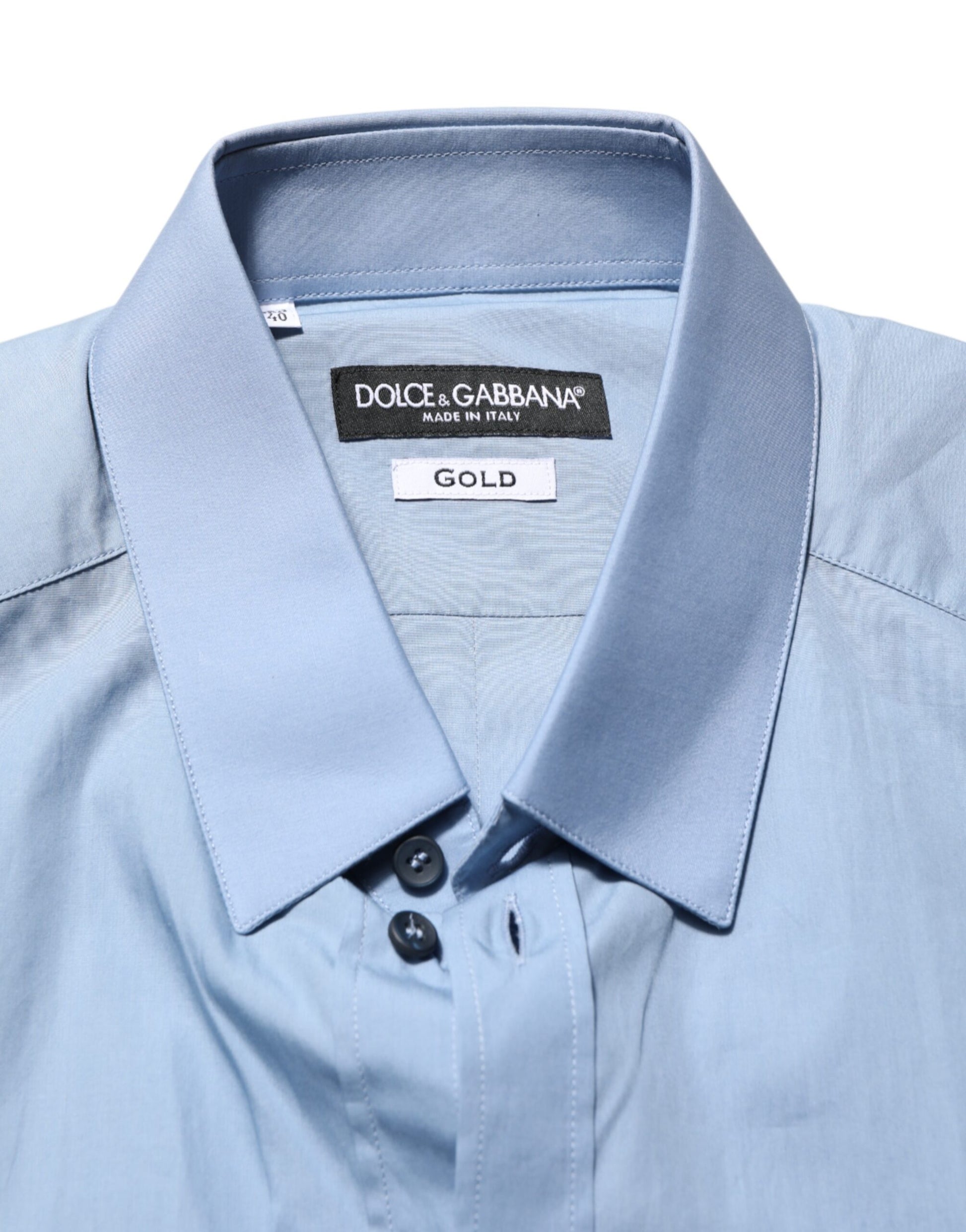 A blue collared shirt with a gold label on the front