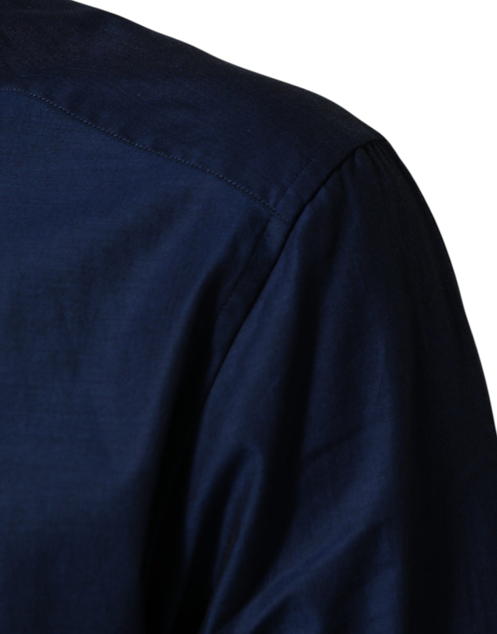 A blue collared dress shirt with a gold emblem on the left chest