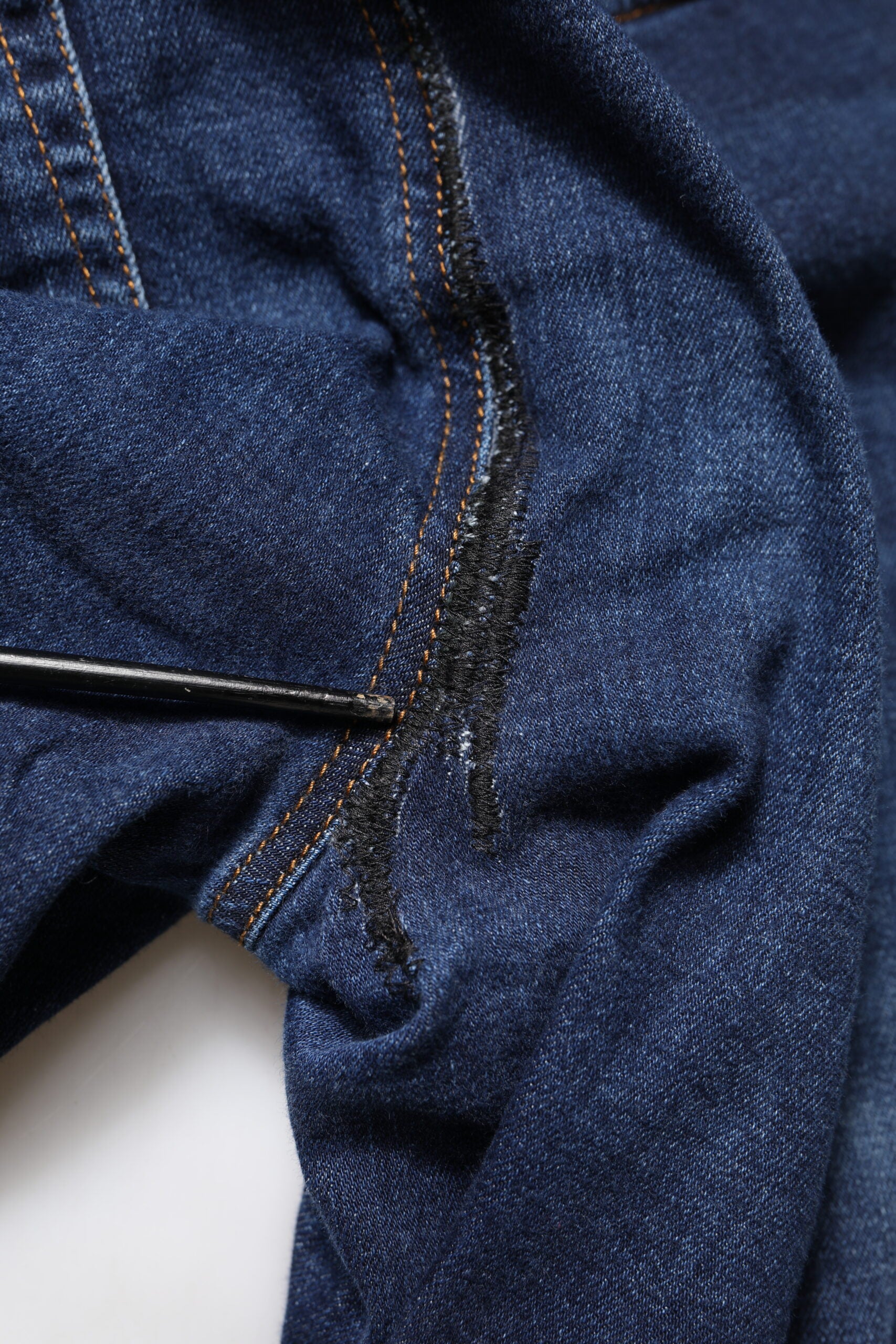 Blue denim jeans with black stitching on waistband