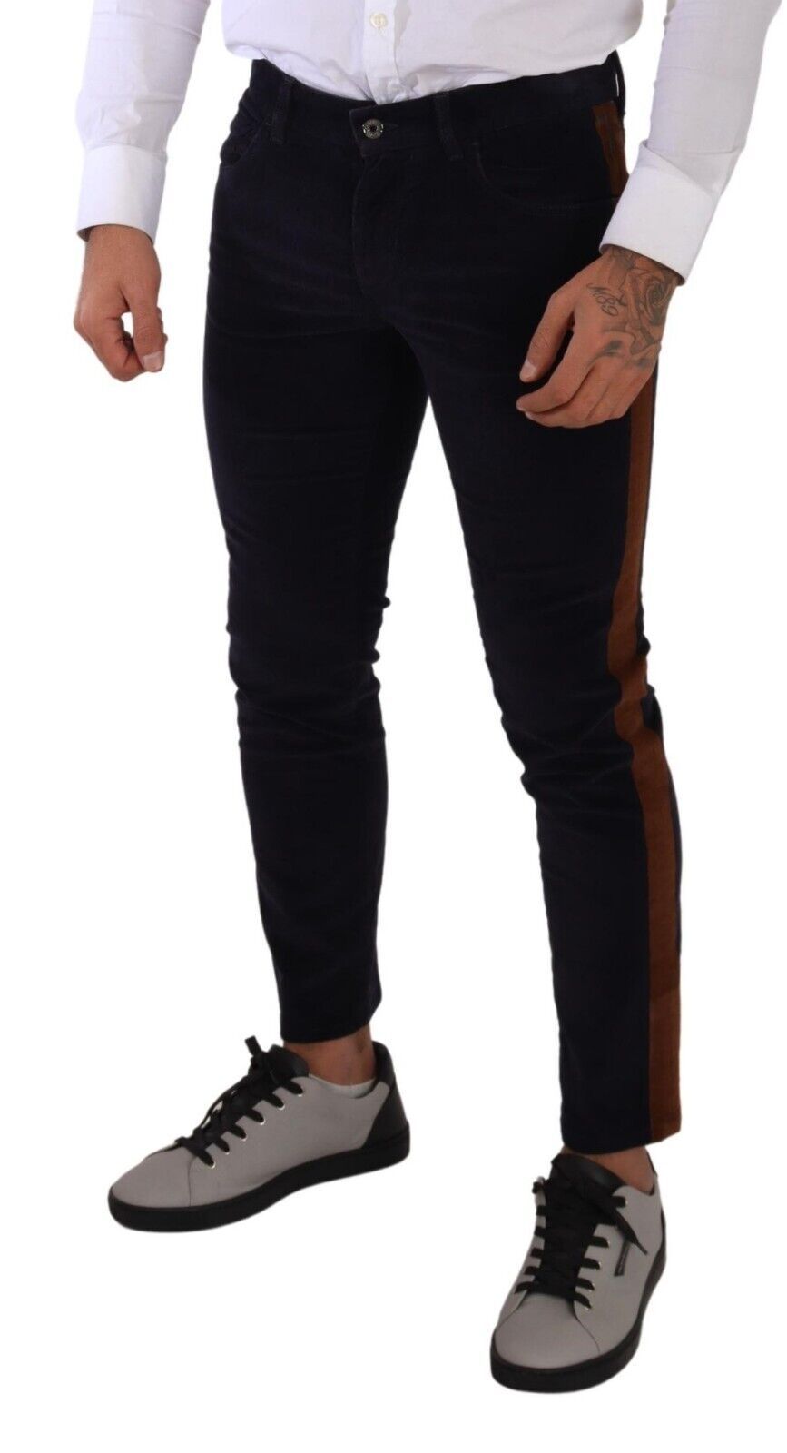 Man wearing black pants with brown stripe down side, white shirt, and grey sneakers