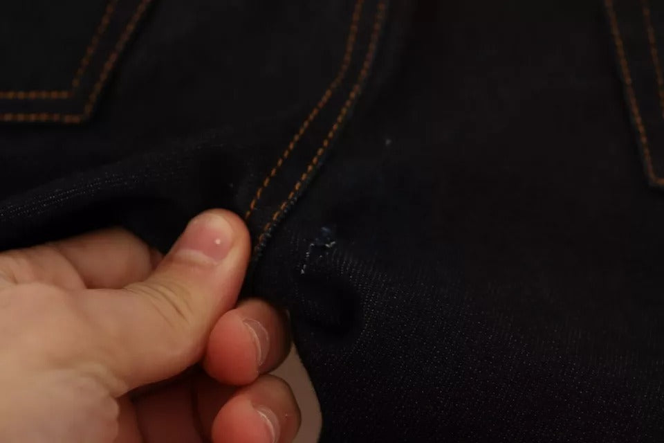 Hand holding a pair of jeans by the waistband
