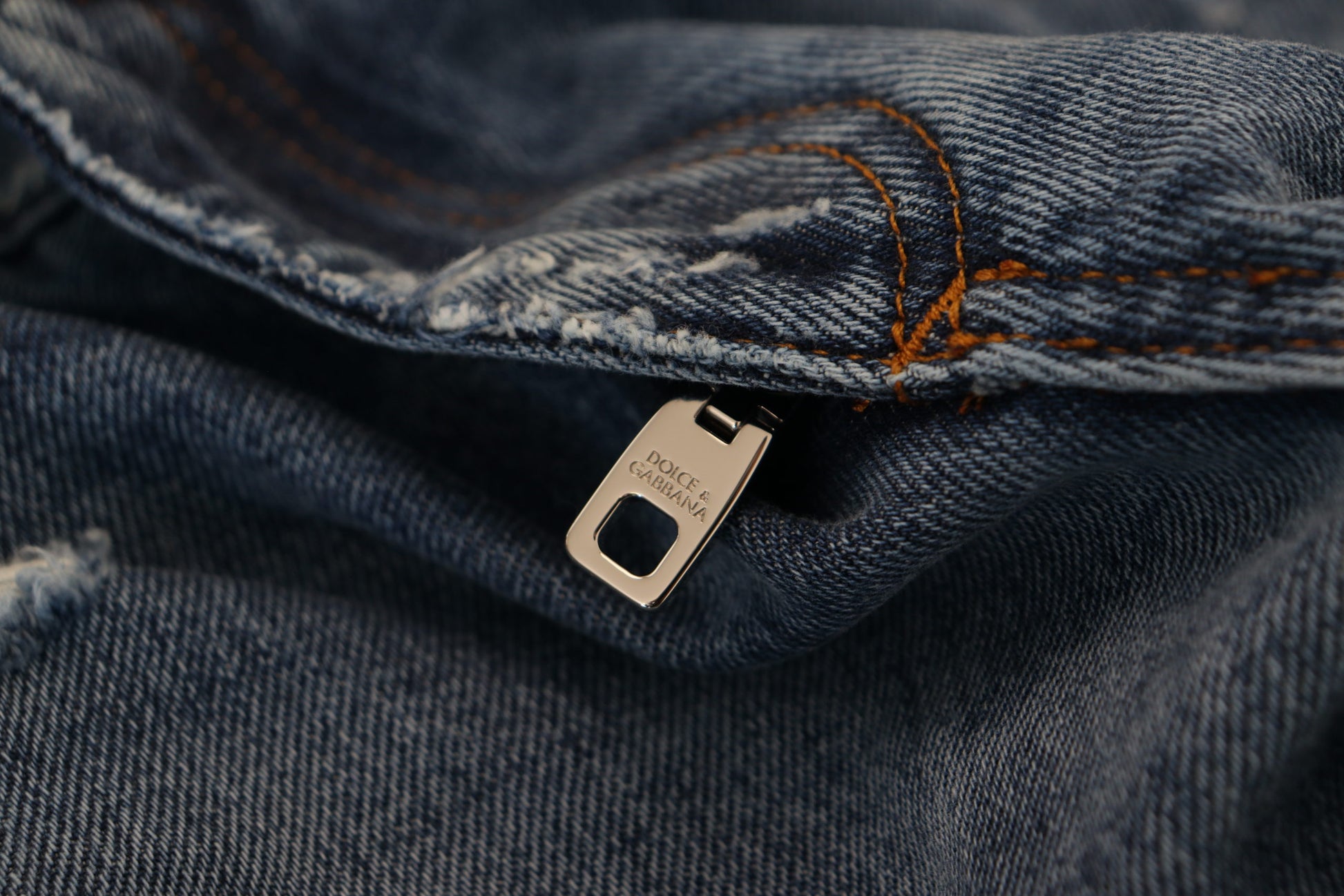 Silver zipper pull on blue jeans