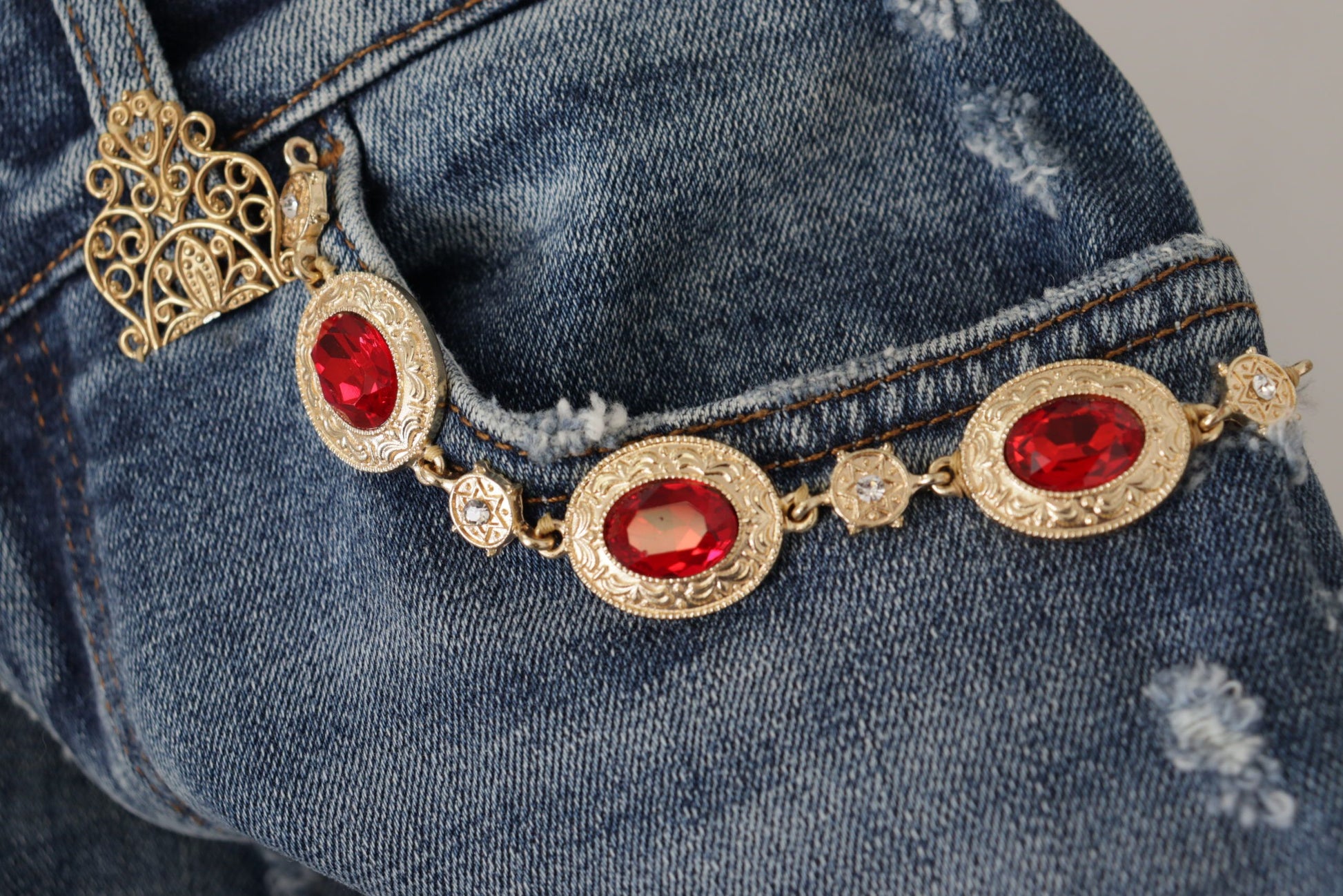 Gold necklace with red stones on denim jeans